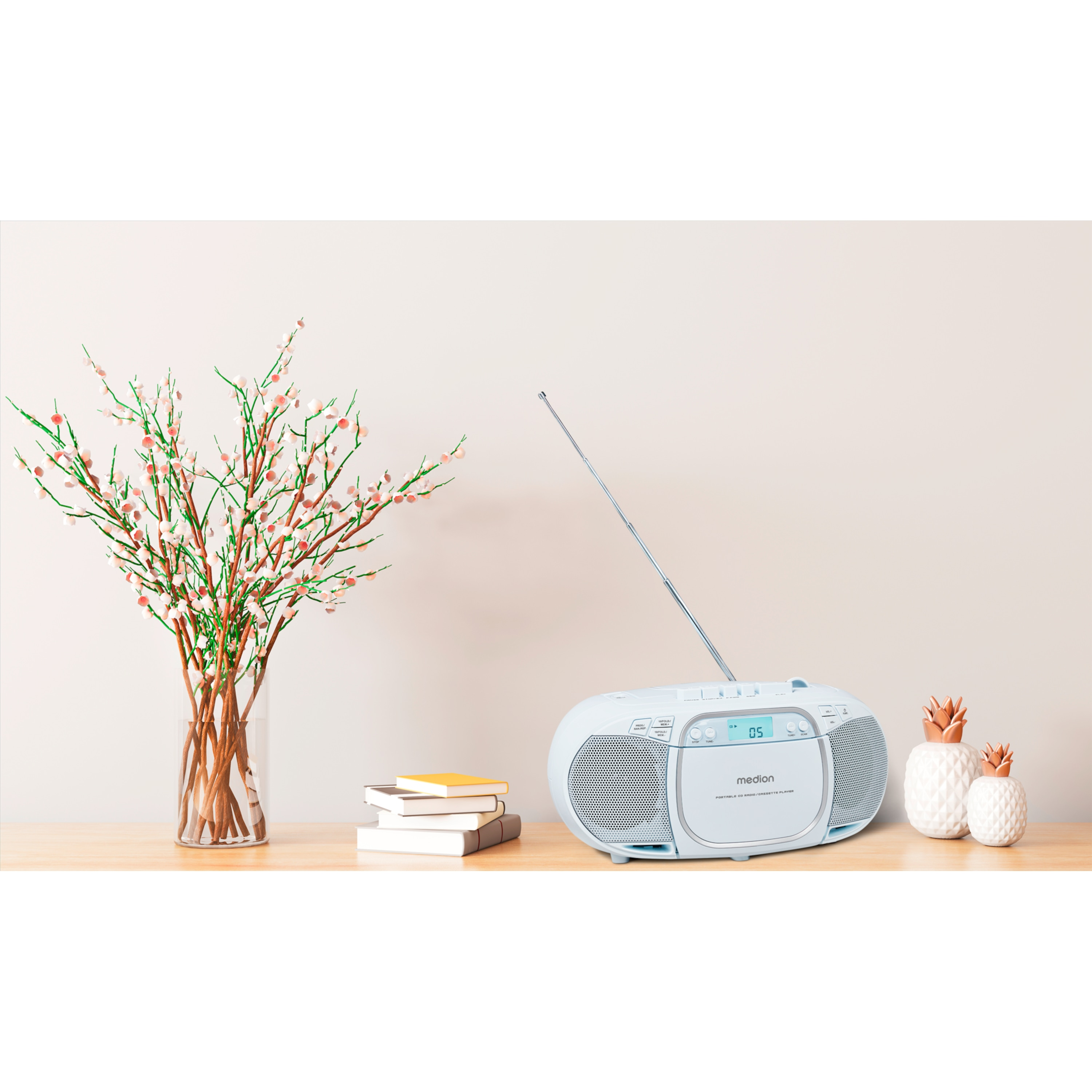 Un boombox azzurro su un tavolo di legno, con fiori e decorazioni sullo sfondo.