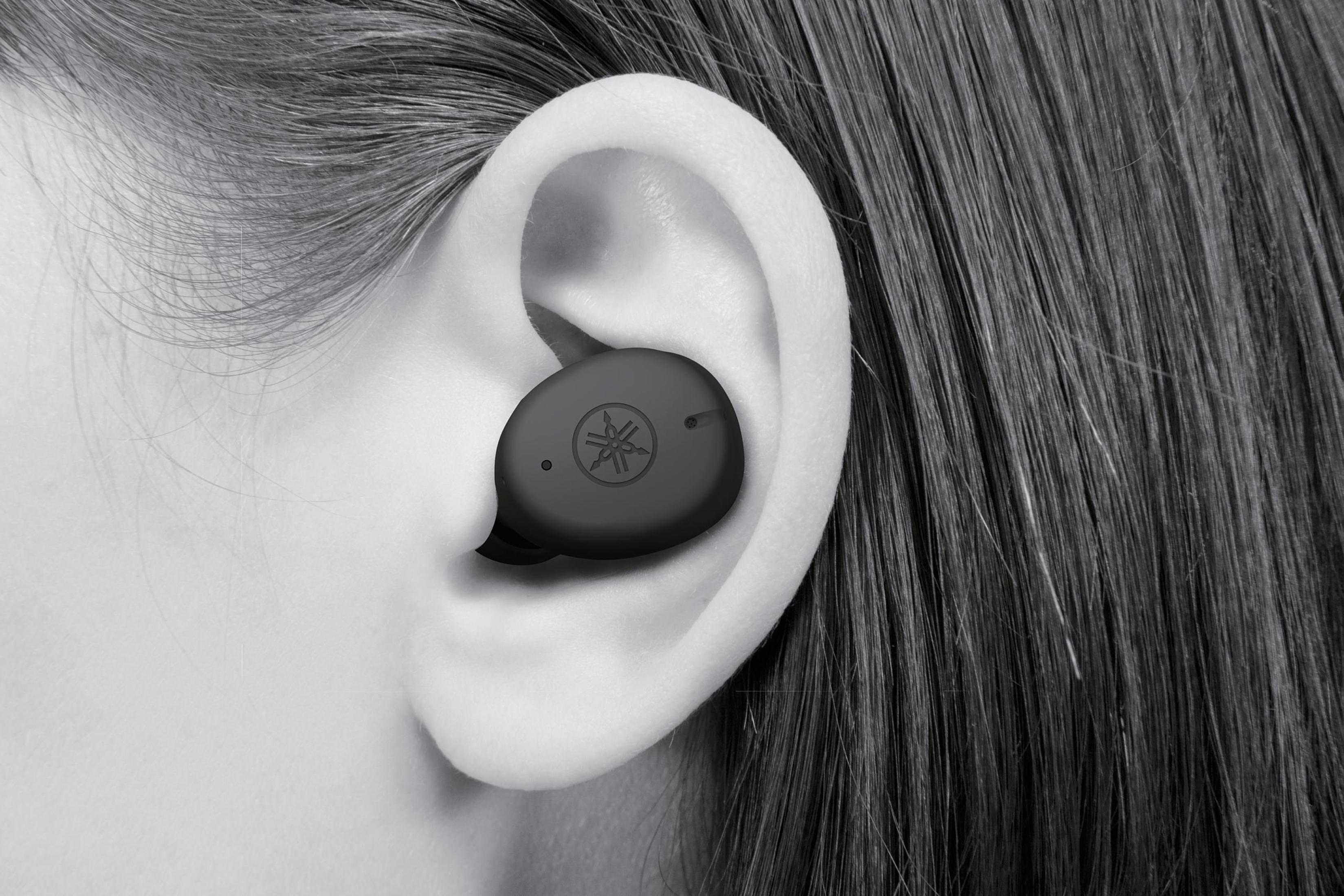 Primo piano di un orecchio con un auricolare nero inserito. L'auricolare ha un logo.