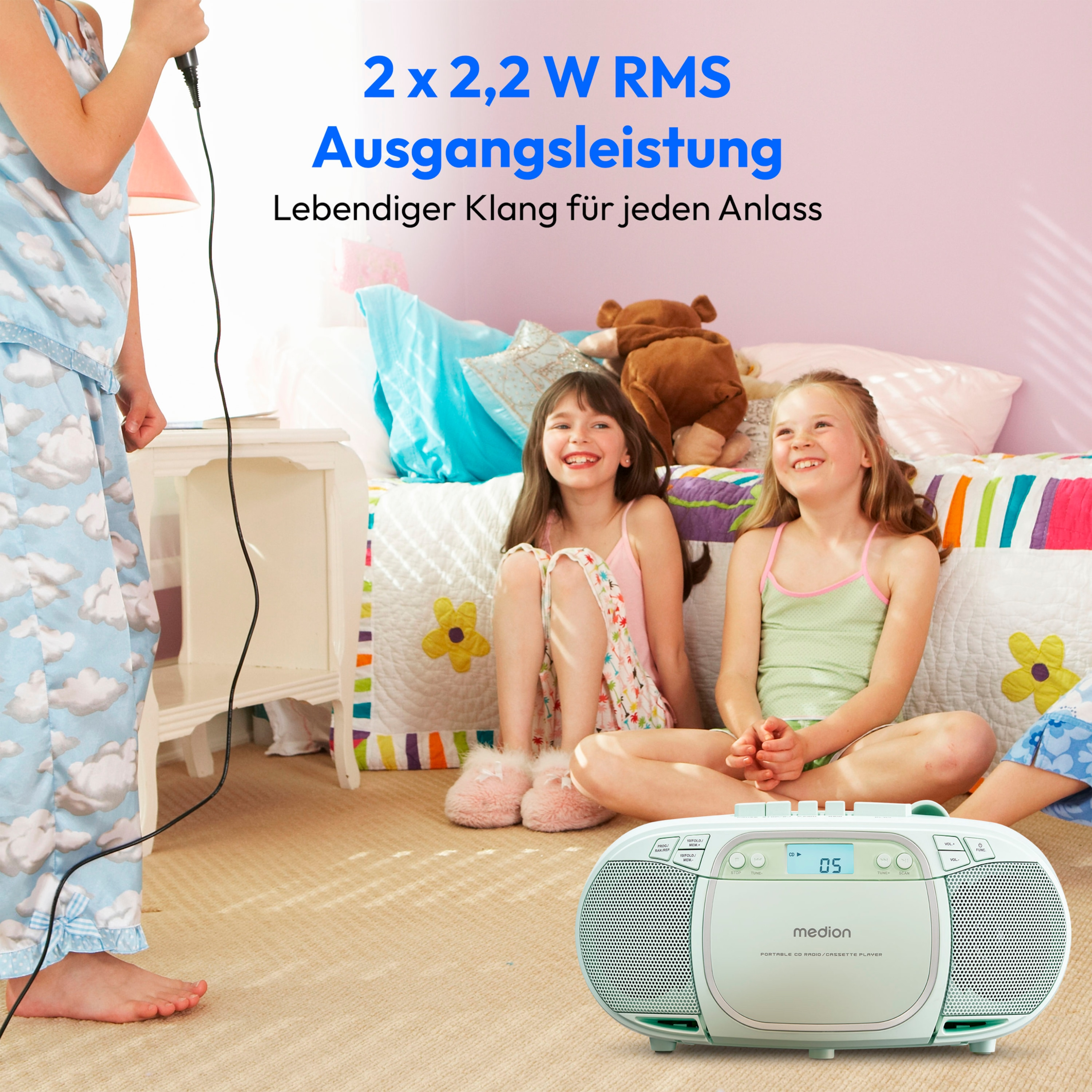 Drei Mädchen mit einer Boombox und einem Mikrofon. Text auf Deutsch: 2x2,2 W RMS Ausgangsleistung.