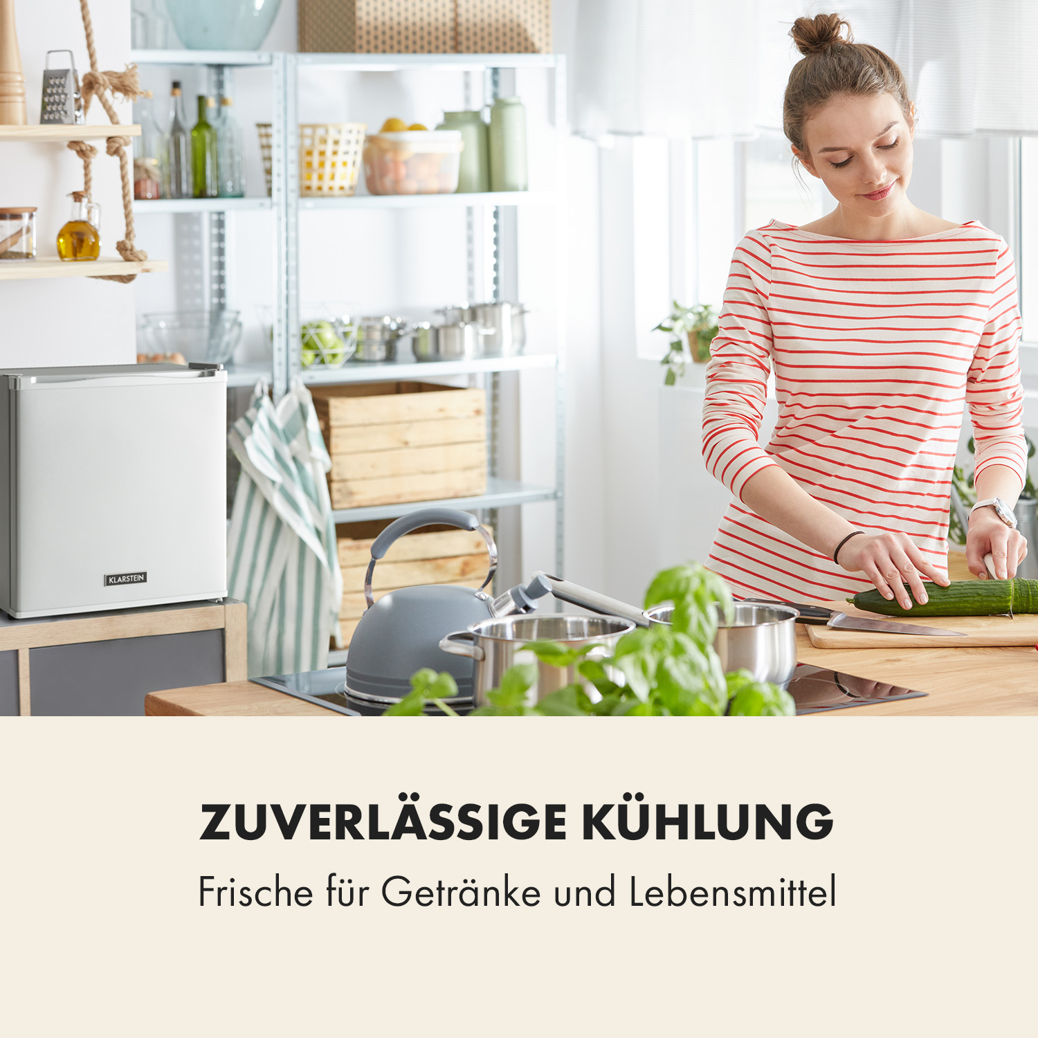 Eine Frau schneidet eine Gurke in einer Küche, links ein Kühlschrank. Im Hintergrund Regale.