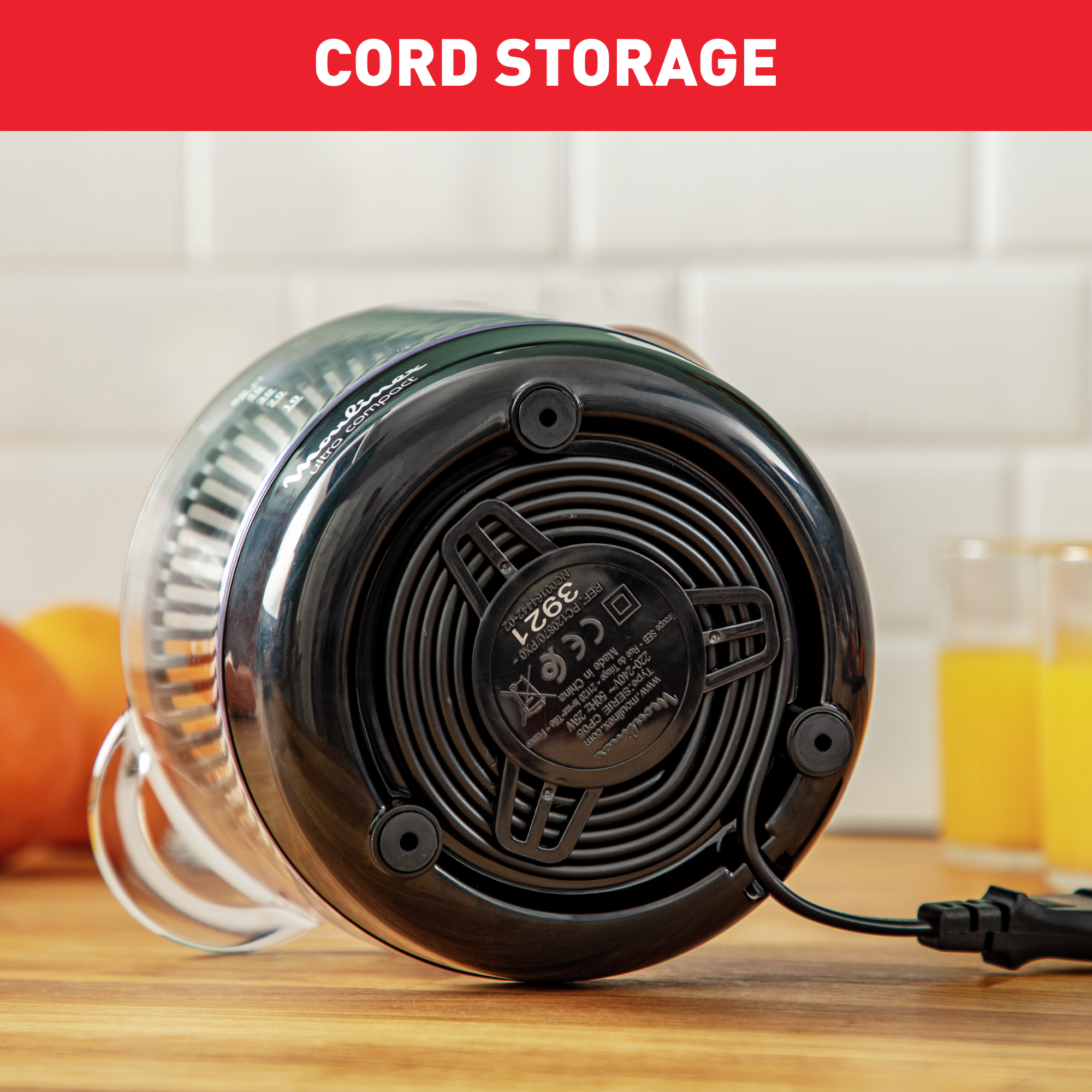 Podstawa wyciskarki, czarna, z przechowywaniem przewodu. Widok z bliska, drewniana powierzchnia, dwie szklanki z sokiem.