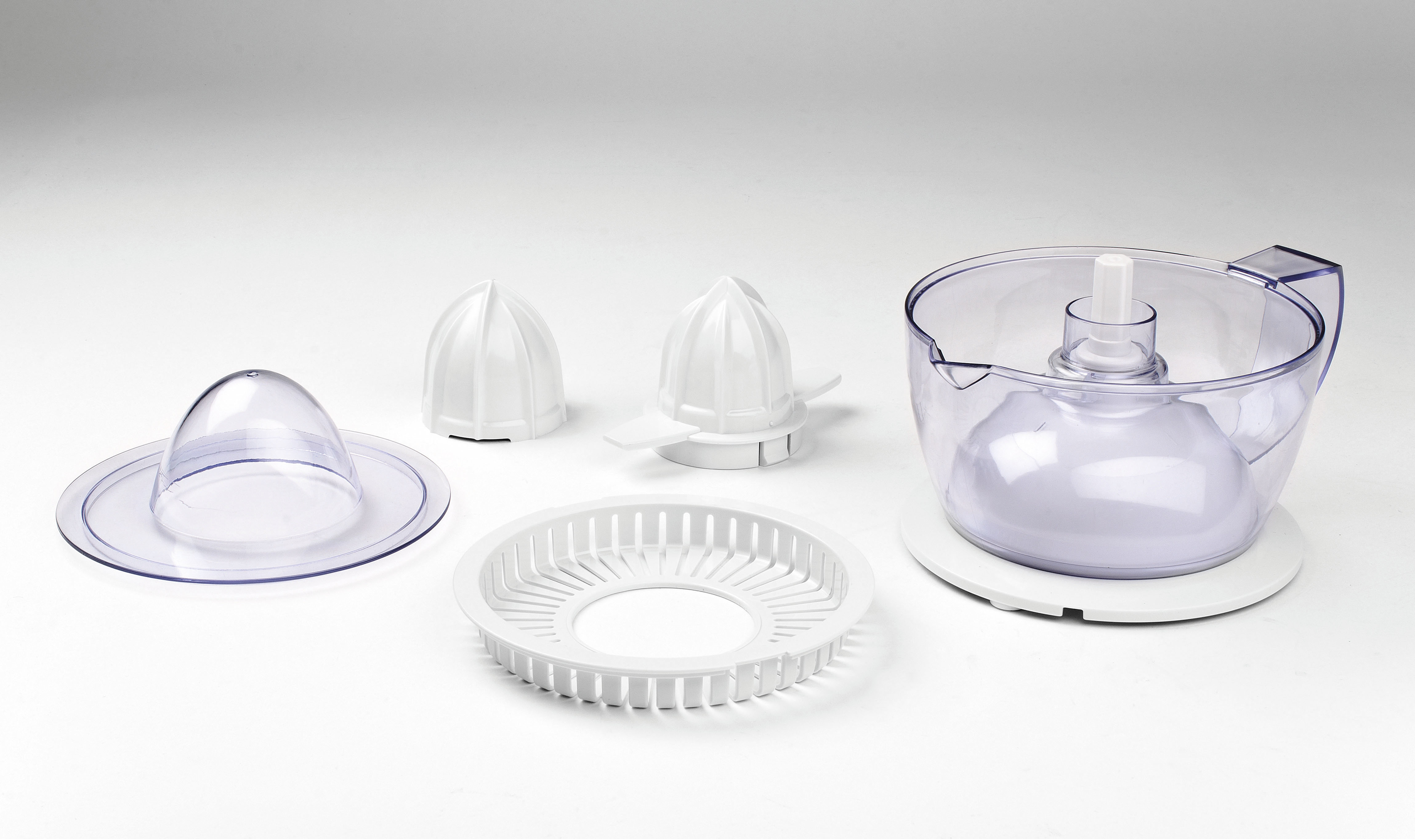 Części wyciskarki na białym tle. Pokazano różne białe elementy plastikowe.