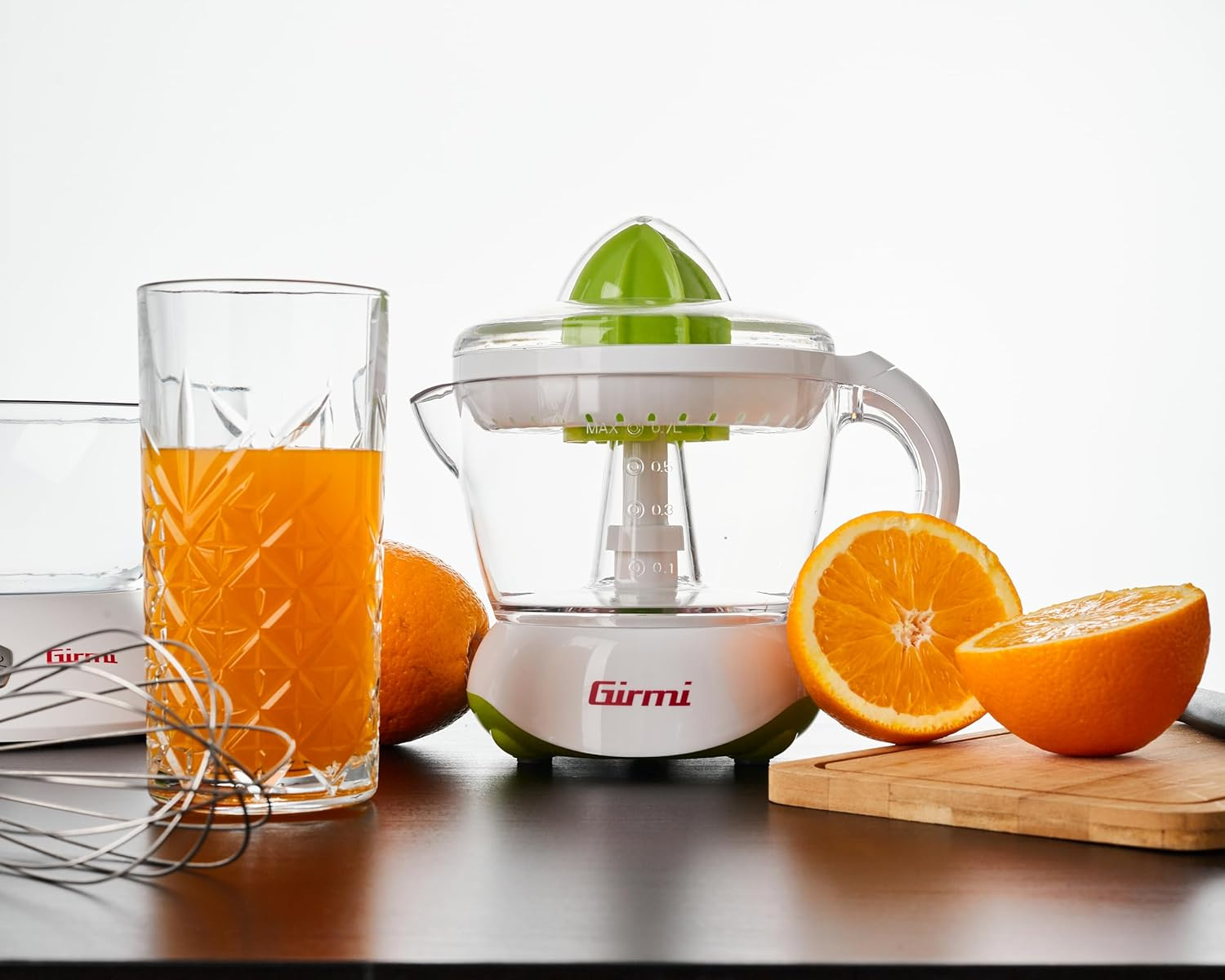 Entsafter mit Orange und Glas Saft. Orangen-Hälften und Schneidebrett sind vorhanden.