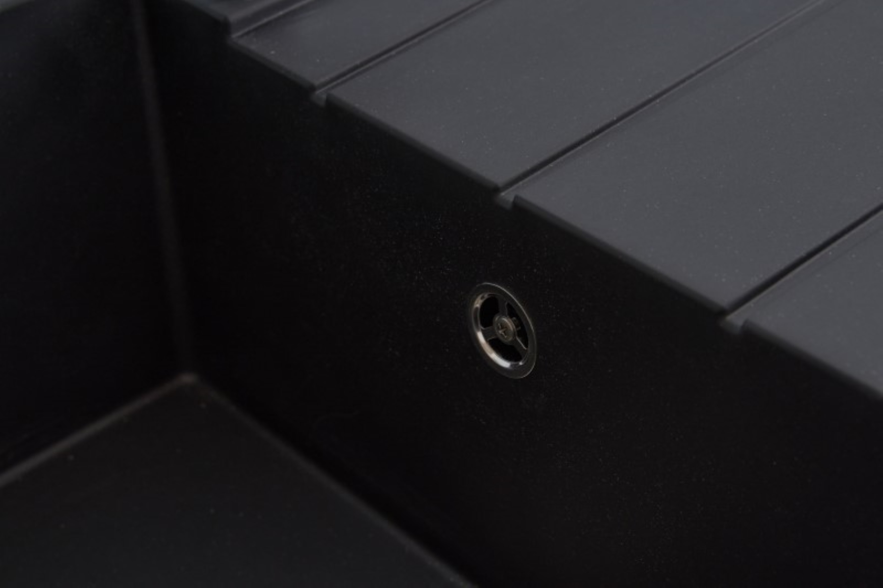 Un primo piano di uno scarico del lavandino nero con un anello di metallo. Il lavandino è nero e ha una superficie piana.
