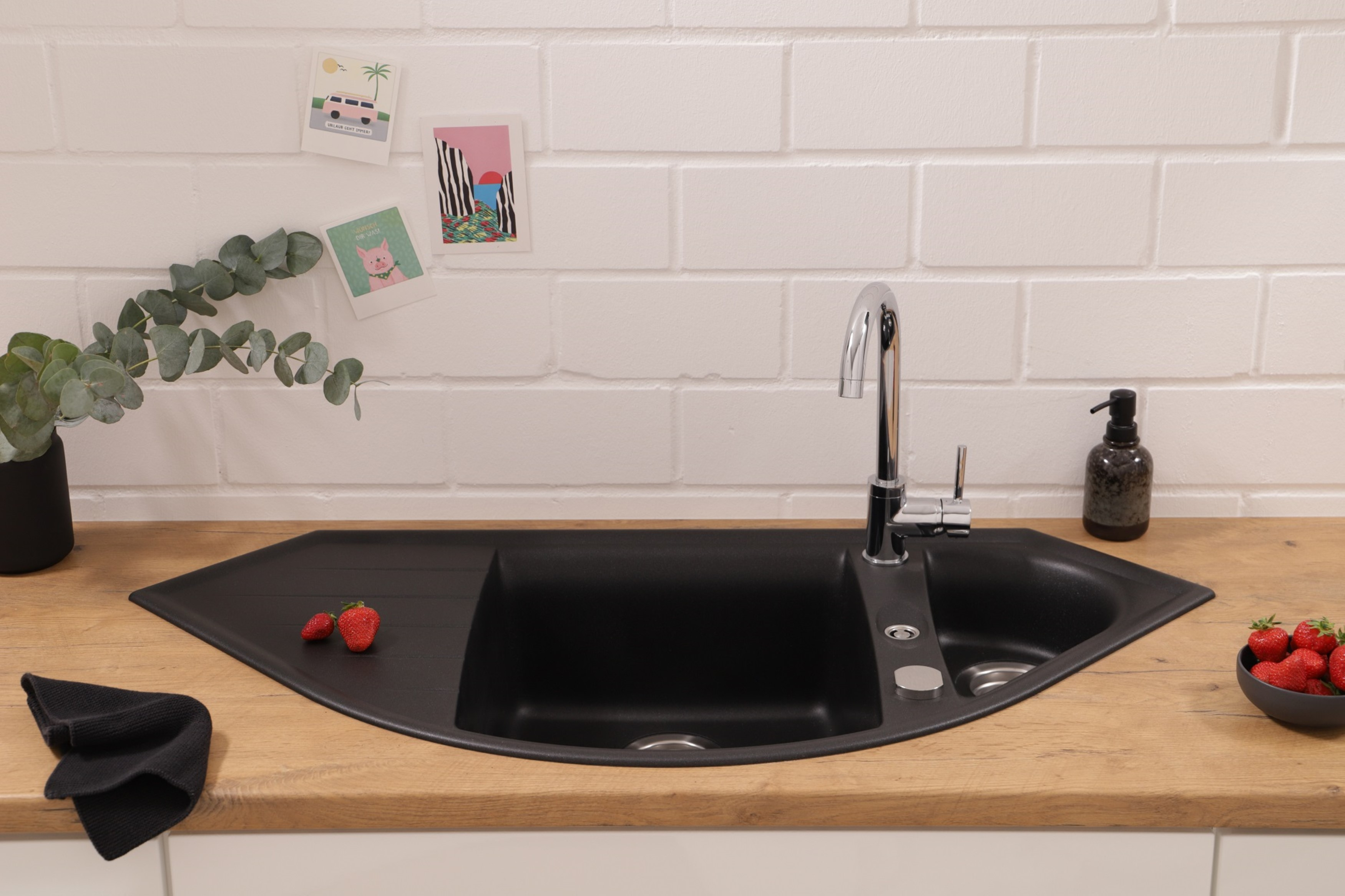 Küchenspüle mit Erdbeeren, Wasserhahn und weißer Ziegelmauer. Holz-Arbeitsplatte.