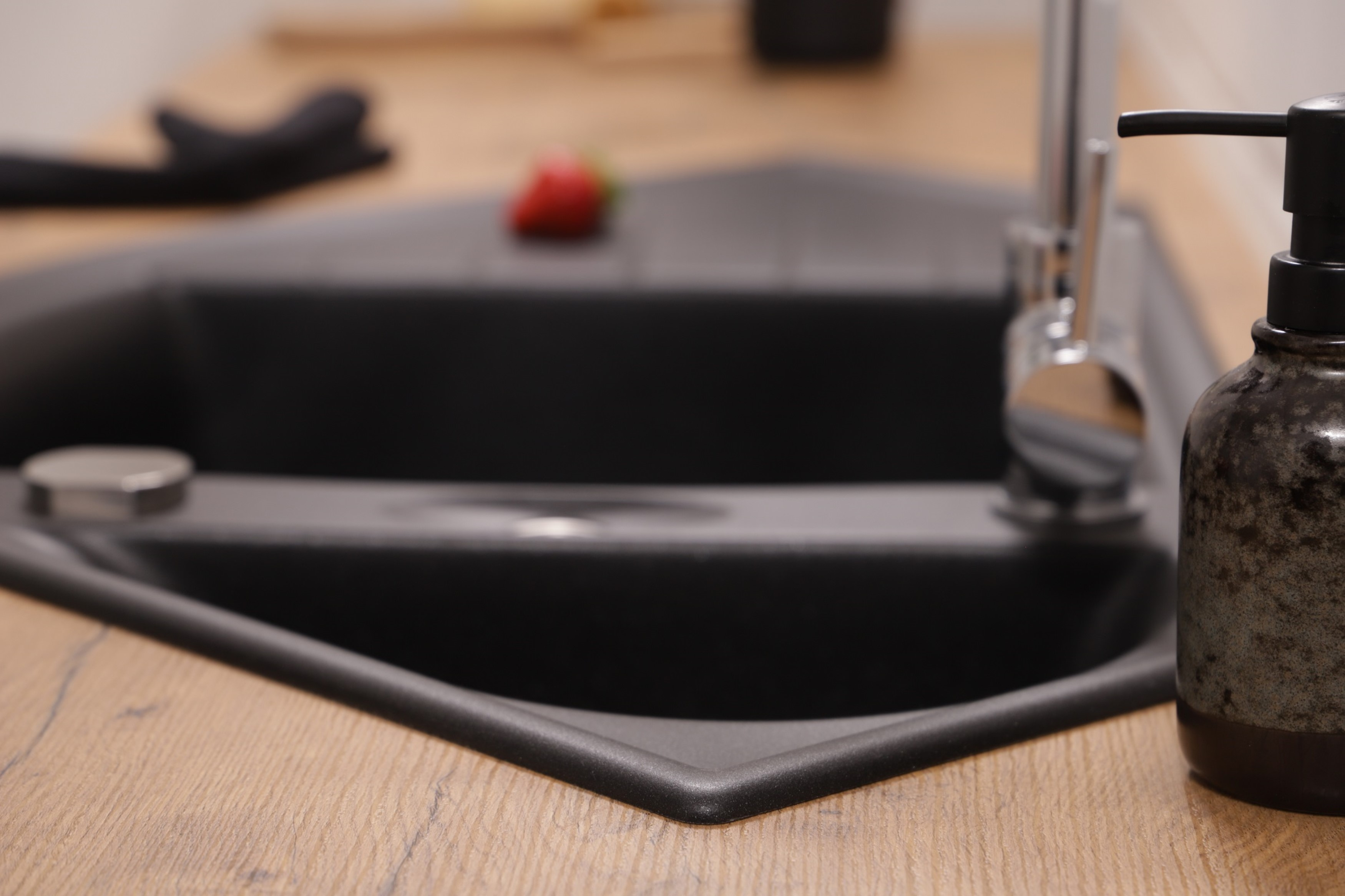 Eine schwarze Senkenecke auf einer Holz-Arbeitsplatte mit Wasserhahn und Seifenspender.
