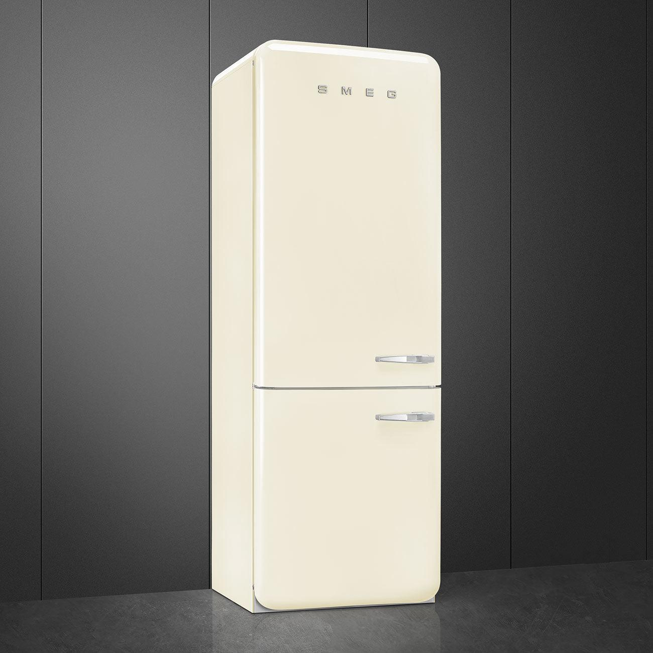 Un refrigerador Smeg color crema contra una pared gris oscuro.