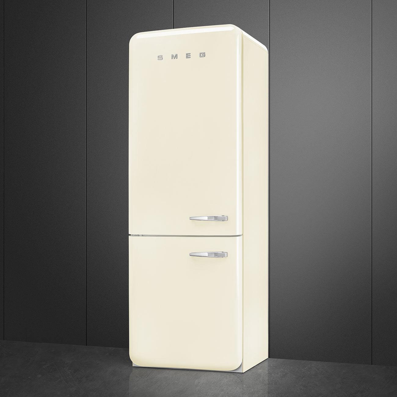 Refrigerador color crema con manijas plateadas. Arriba está la marca SMEG, contra una pared gris oscura.