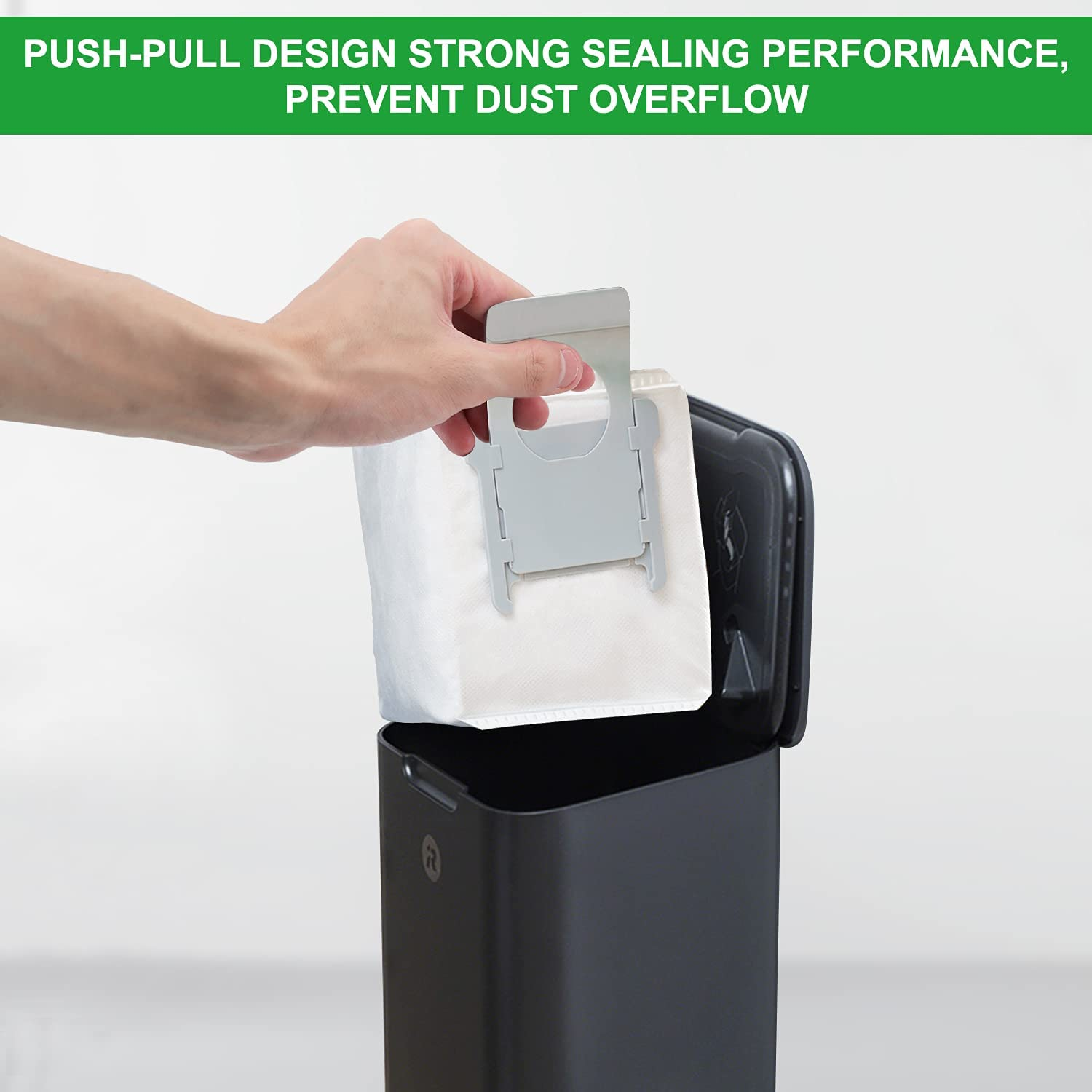 Ręka wyjmująca biały worek na kurz z czarnego odkurzacza.