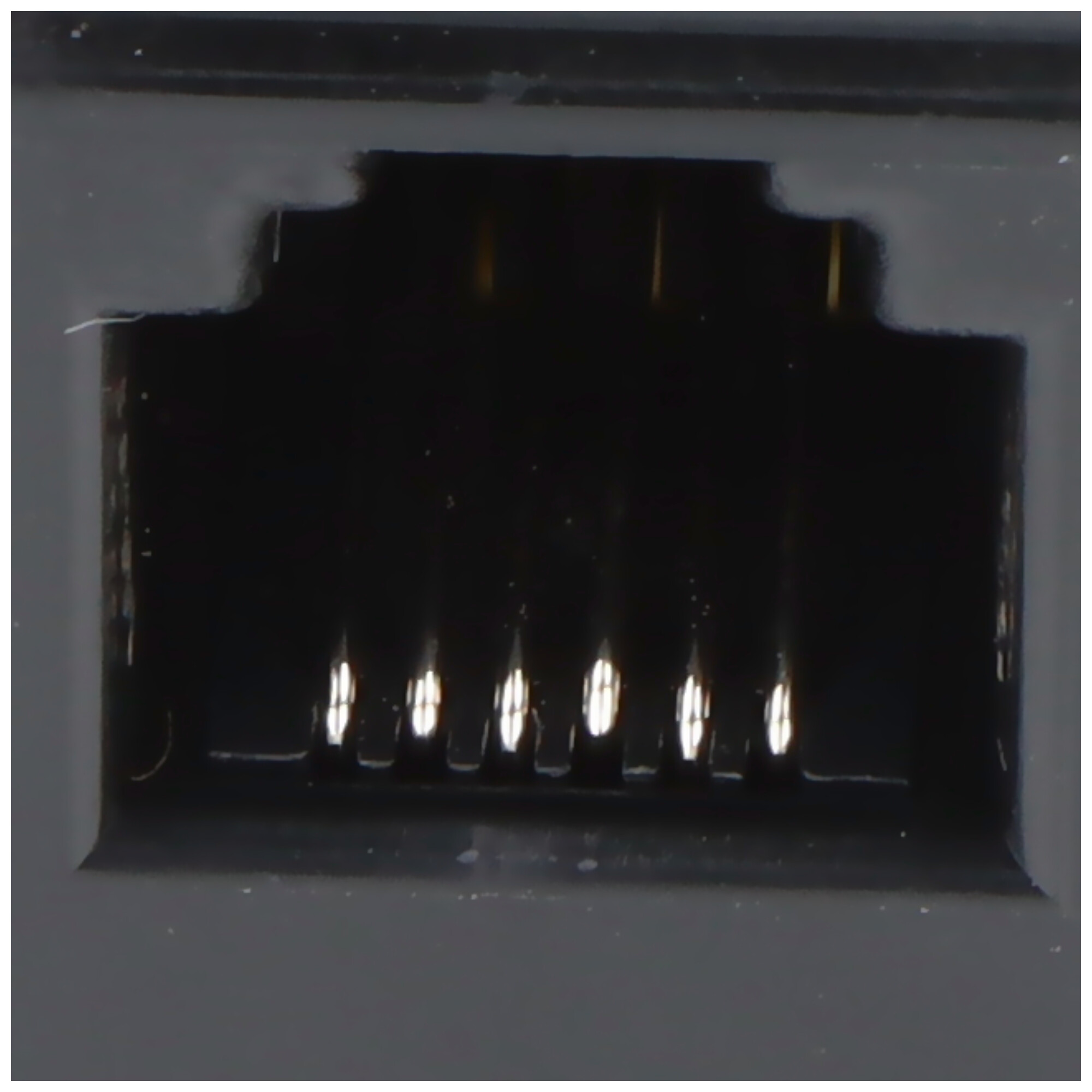 Nahaufnahme eines schwarzen Netzwerkanschlusses mit 8 goldenen Pins auf schwarzer Oberfläche.