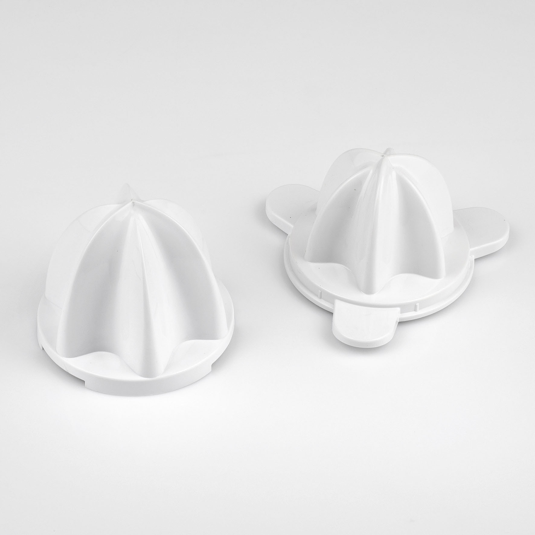 Dwie białe części wyciskarki do cytrusów na białej powierzchni.