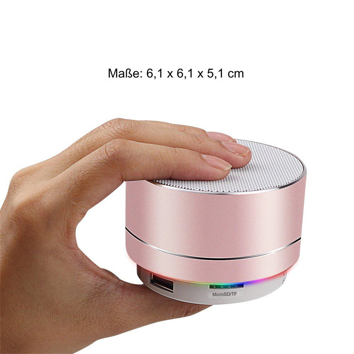 Eine Hand hält einen kleinen, rosa, runden Lautsprecher. Der Lautsprecher hat einen silbernen Deckel.