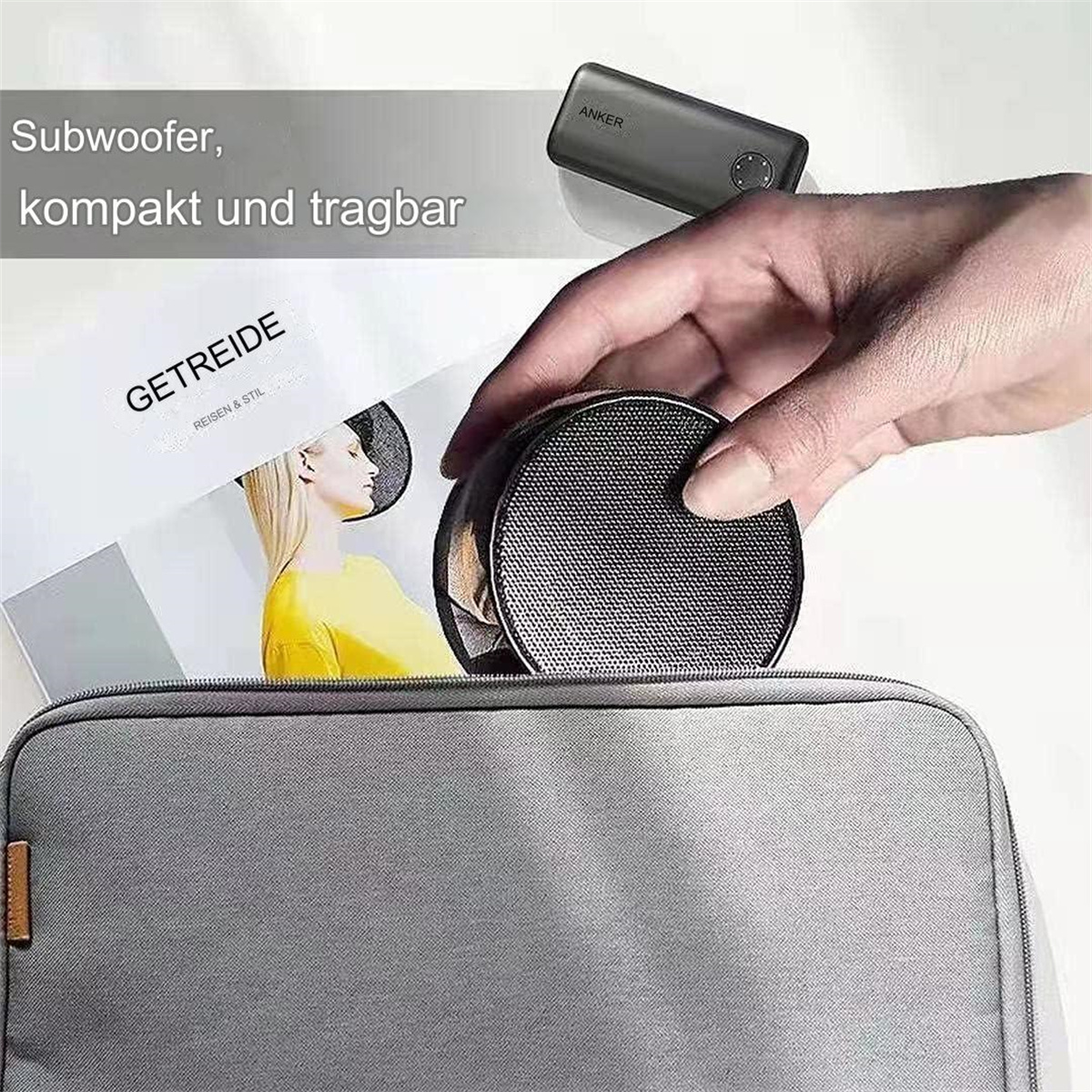 Tragbarer Lautsprecher in grauer Tasche, neben einer Zeitschrift. Text: Subwoofer, kompakt und tragbar.
