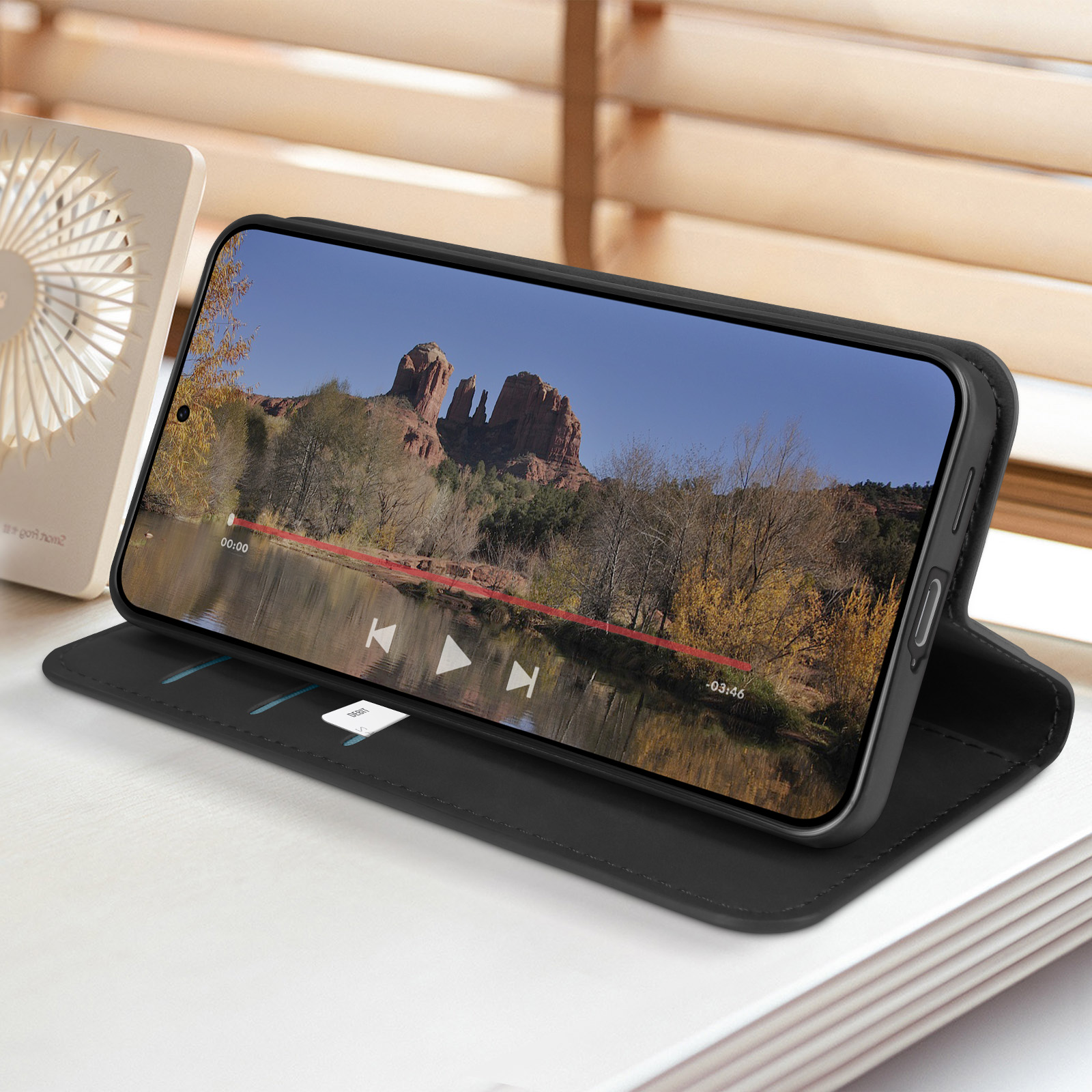Un telefono mostra un video con una vista panoramica, appoggiato su una custodia nera.