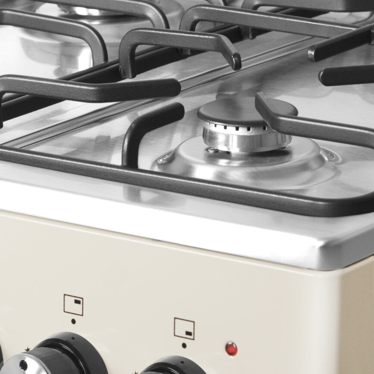 Close-up of a stove top with burners and dials. The surface is light beige.