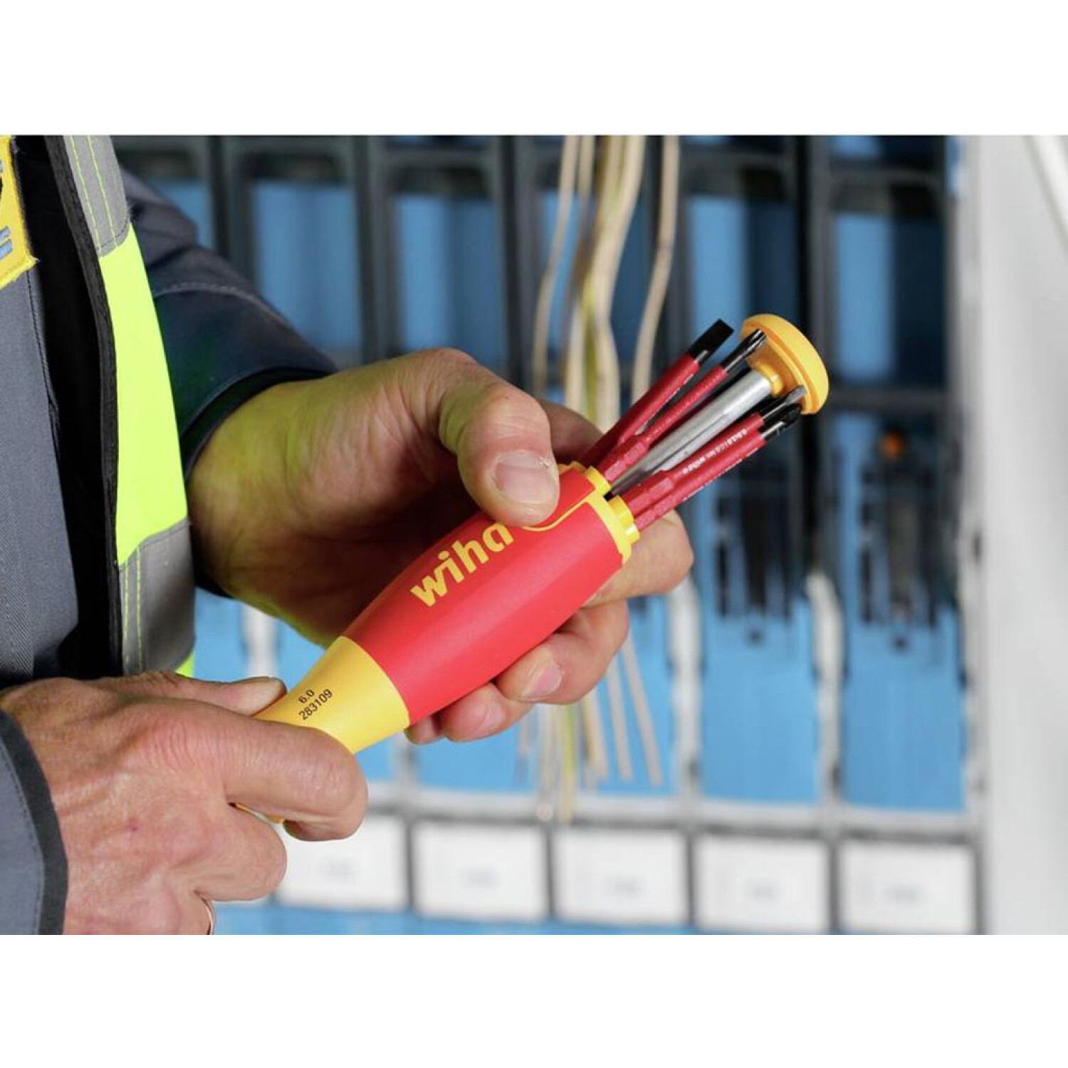 Osoba trzyma czerwono-żółty śrubokręt Wiha z wieloma bitami.