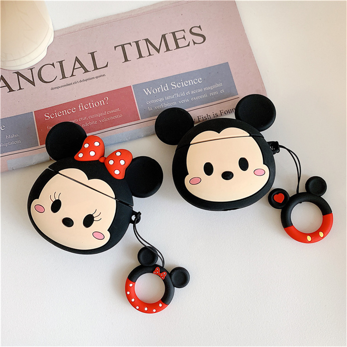 Zwei Mickey-Mouse-AirPods-Hüllen, schwarz mit roter Schleife und rotem Kreis, und ein Mickey-Mouse-Ring.