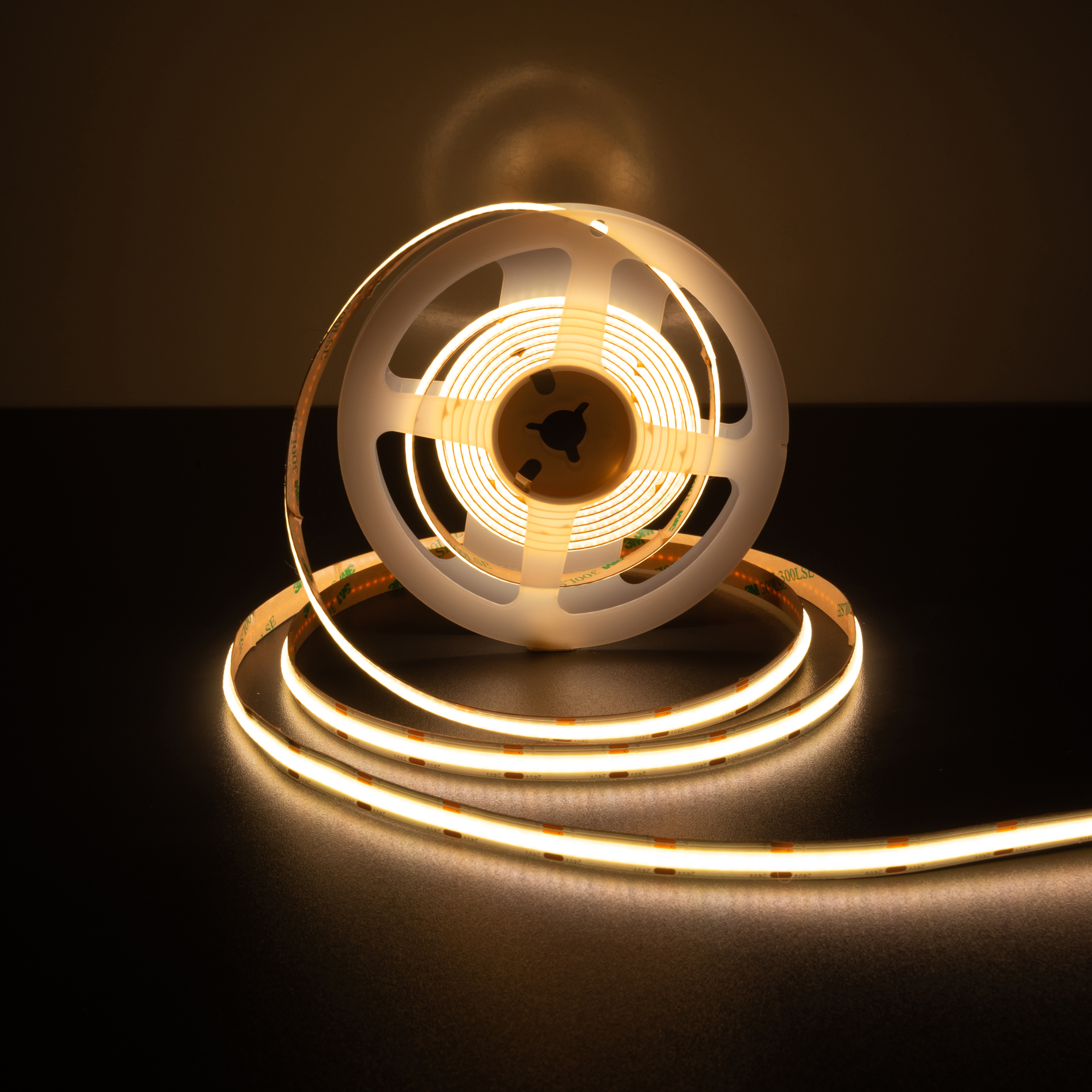 Rolle mit LED-Lichtstreifen. Das Licht ist warmgelb. Der Hintergrund ist eine dunkelgraue Oberfläche.