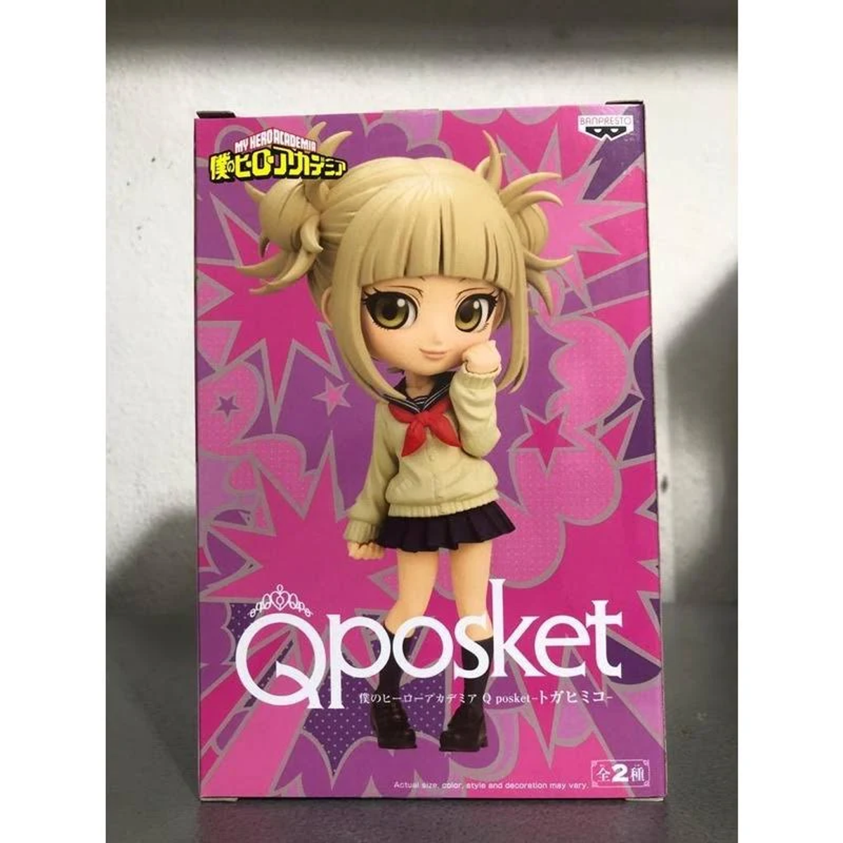 Figura de una chica con pelo rubio en uniforme escolar, en una caja rosa y blanca.