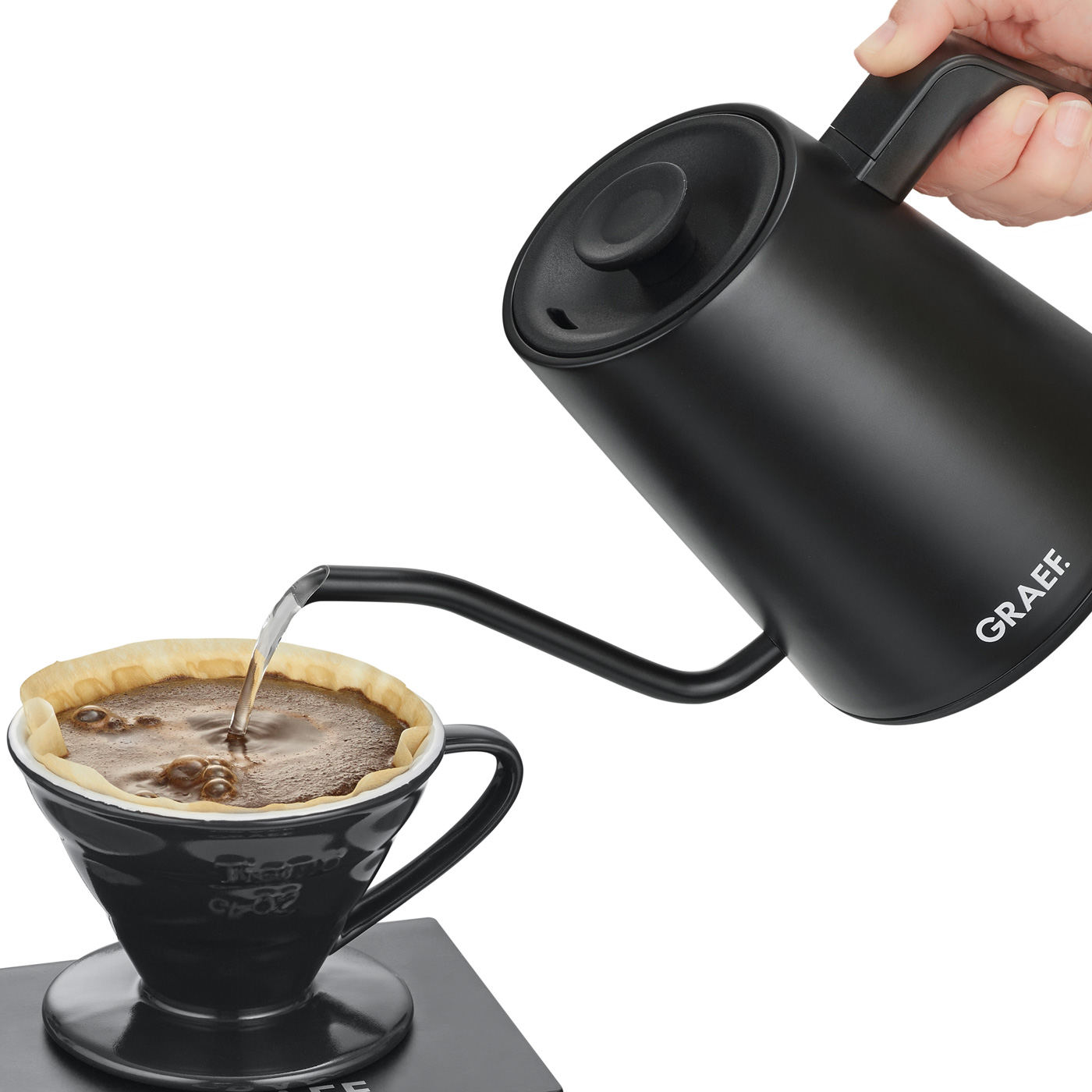 Schwarzer Wasserkocher gießt Wasser in einen schwarzen Kaffeefilter mit Kaffee.