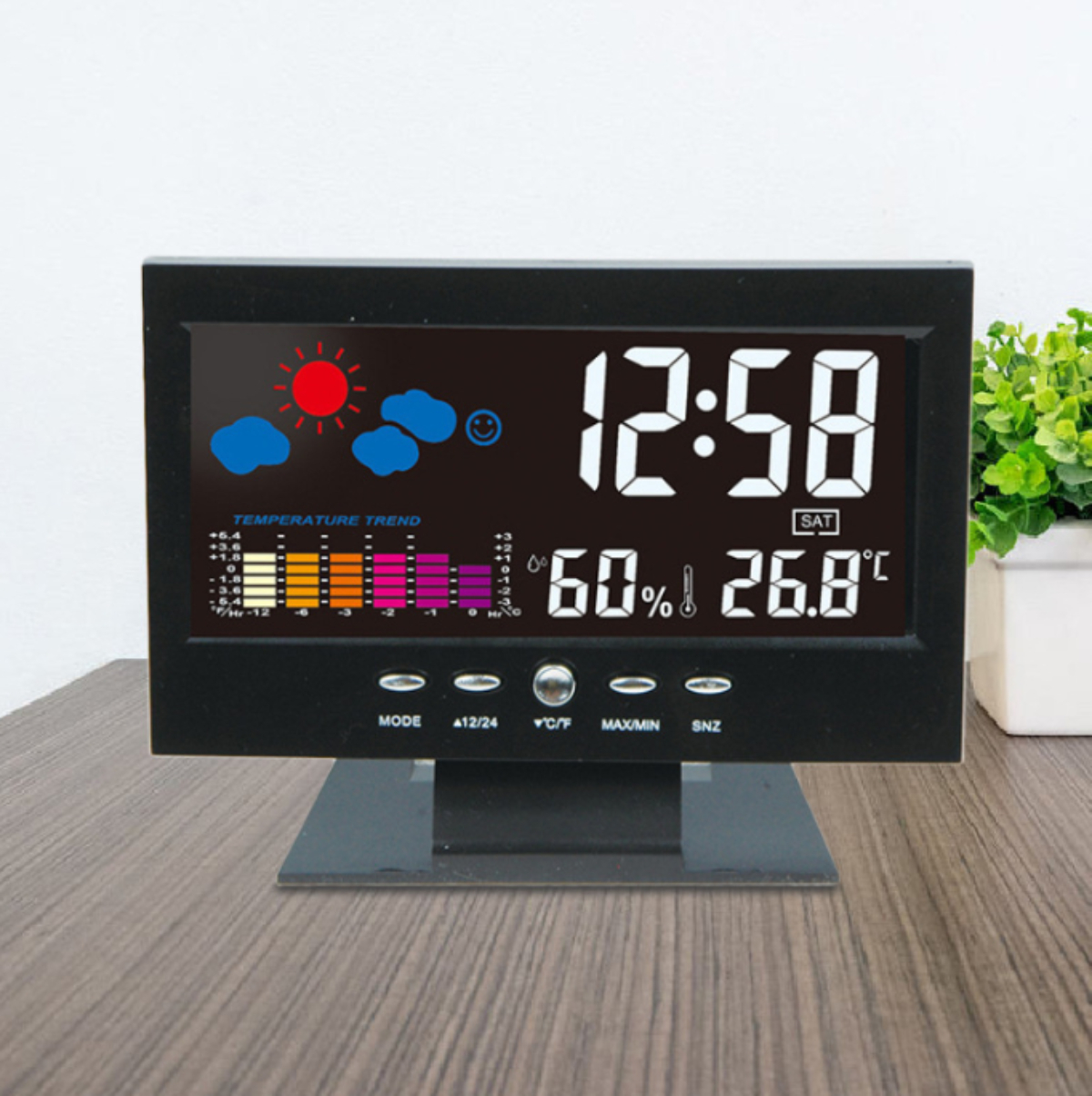 Digitaluhr mit Zeit, Temperatur und Wettersymbolen. Schwarzer Rahmen, Holzoberfläche.
