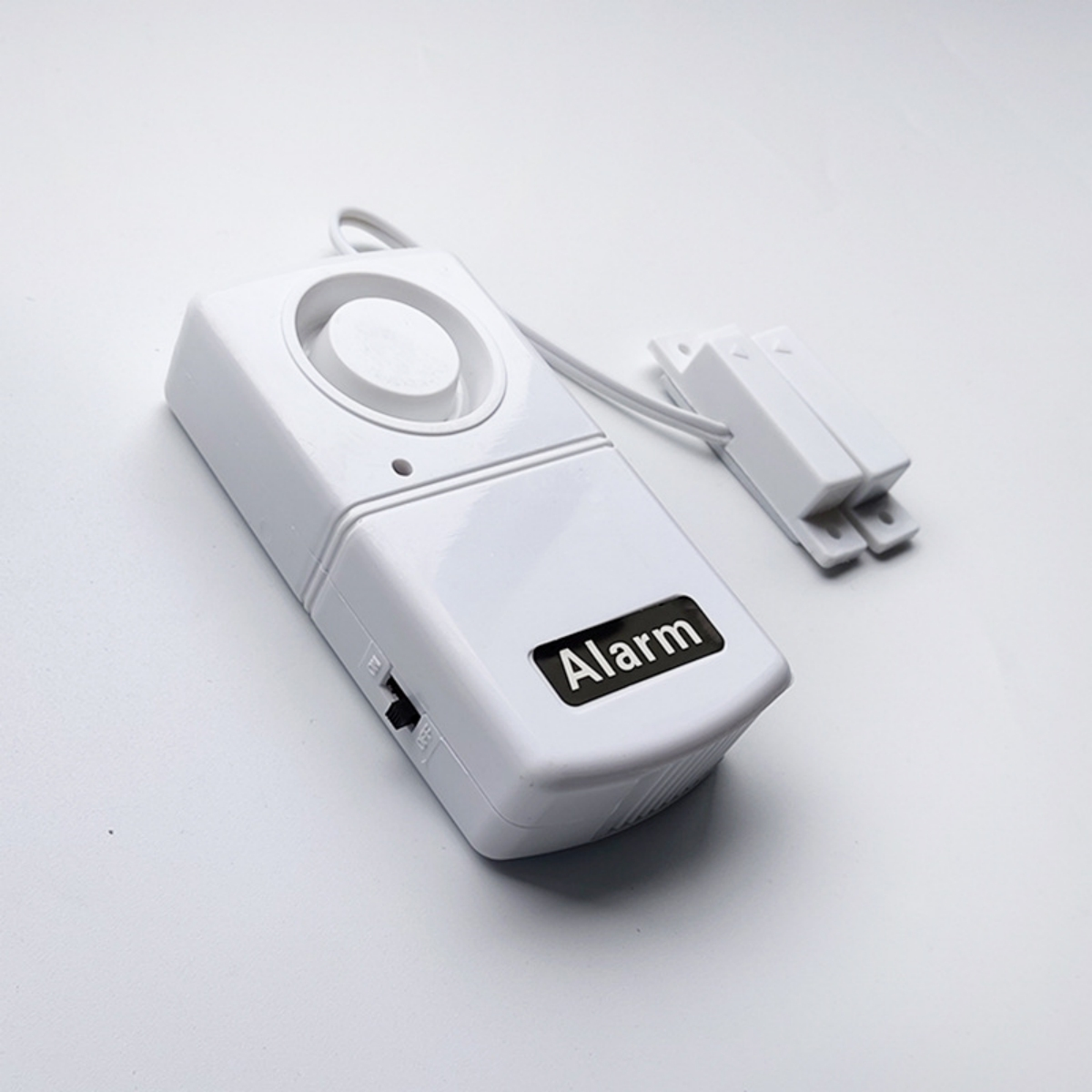 Ein weißes Alarmsystem mit dem Text 'Alarm'. Es enthält einen Magnetsensor und einen kleinen Schalter.