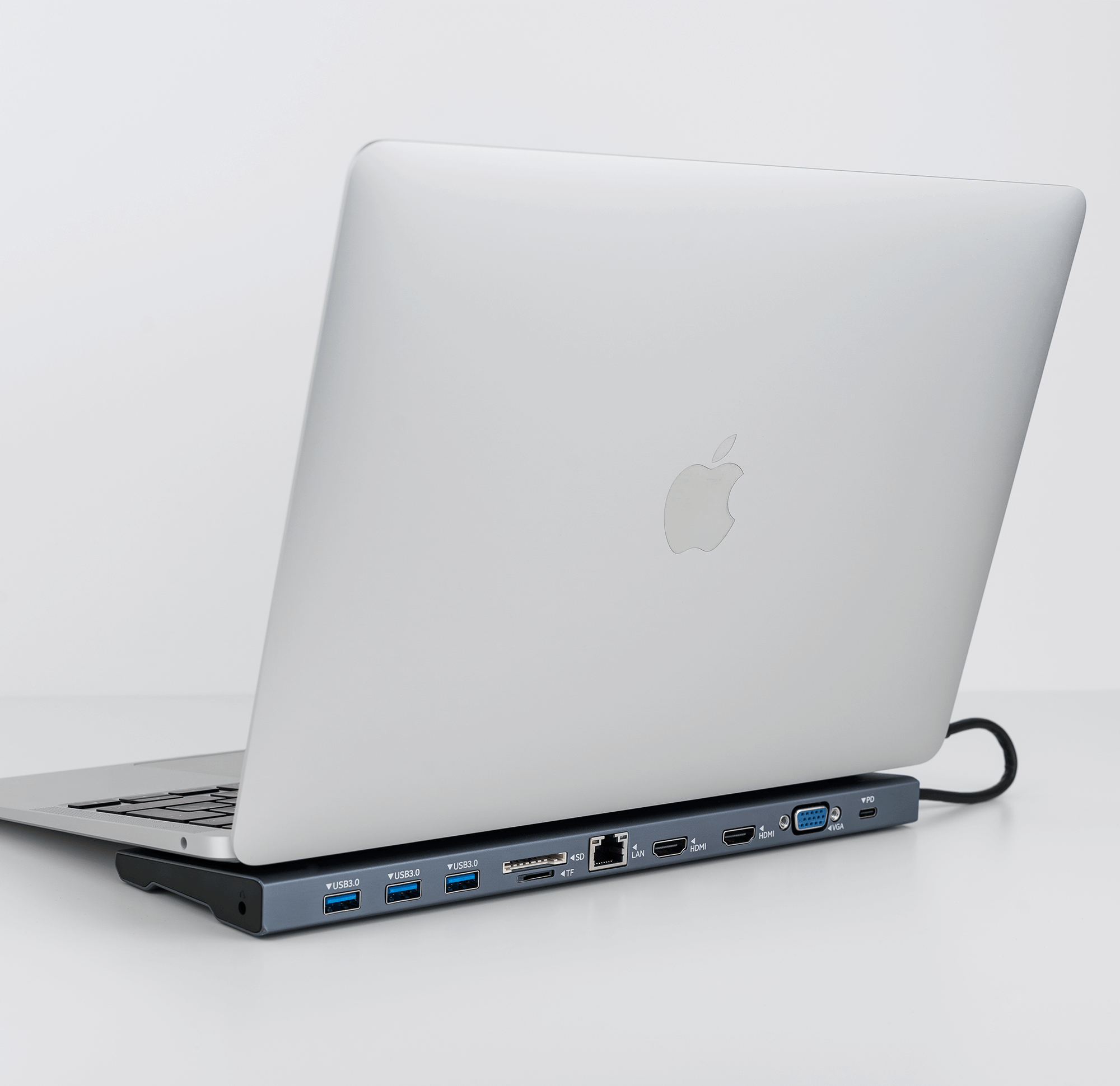 Laptop podłączony do stacji dokującej na białej powierzchni, białe tło.