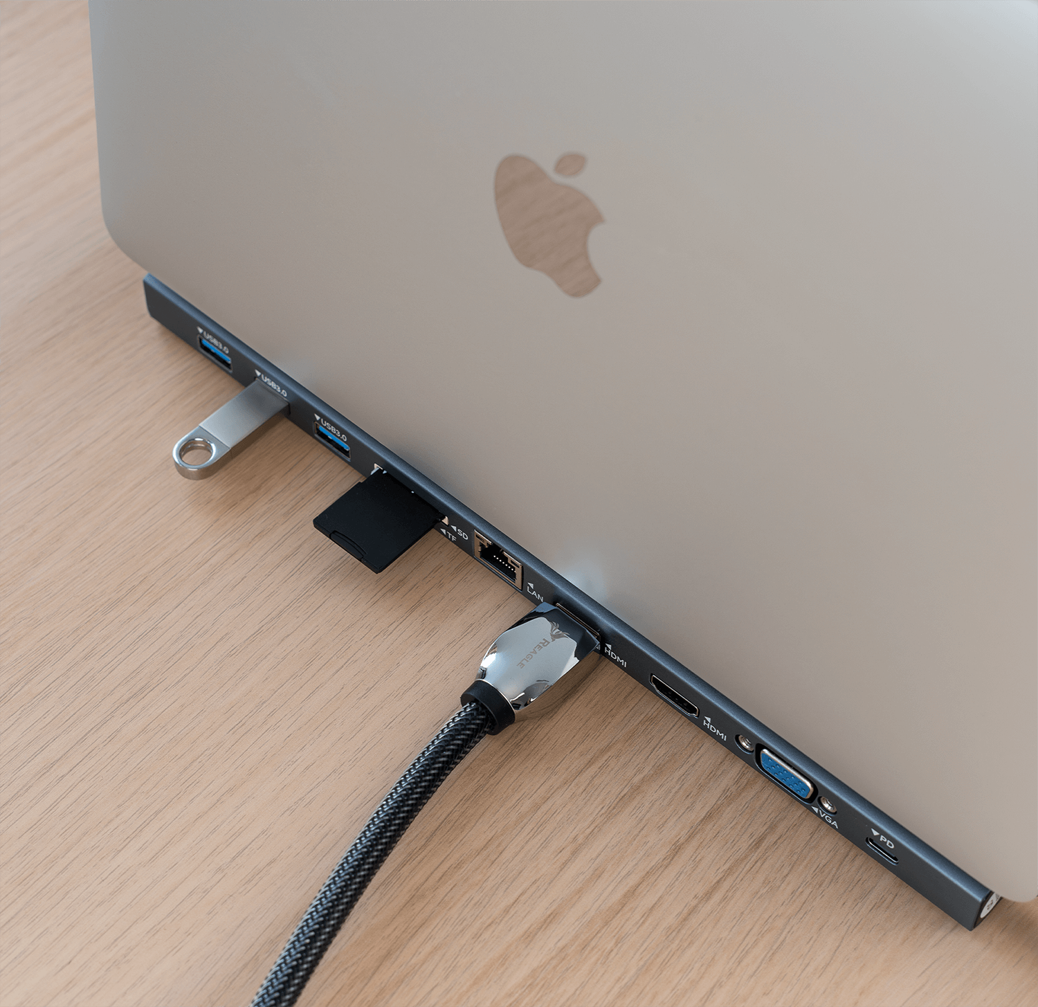 Laptop podłączony do huba z wieloma portami, w tym USB i HDMI.