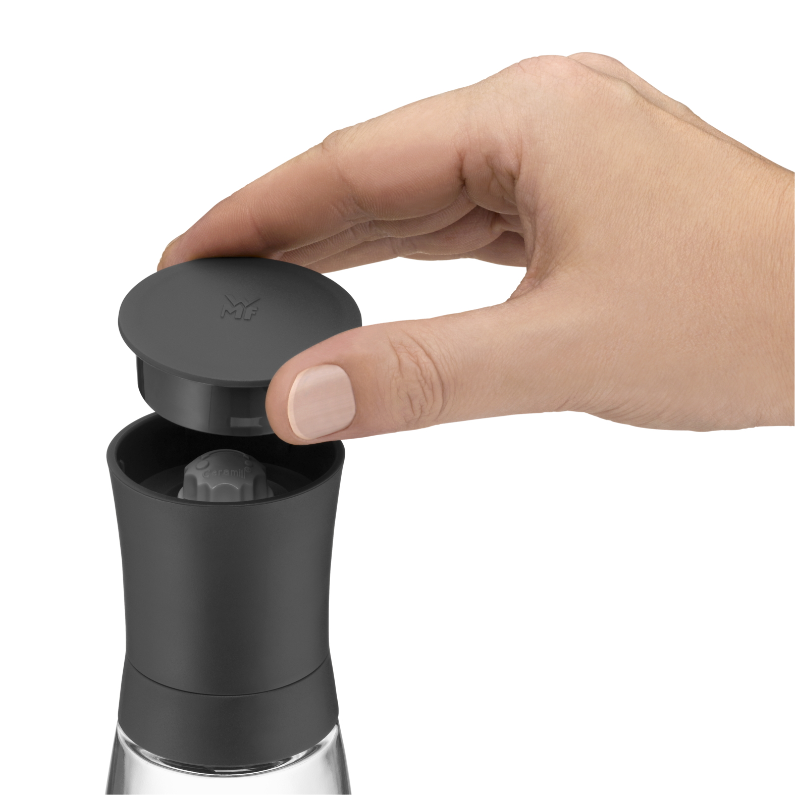 Eine Hand öffnet eine Pfeffermühle. Schwarze und Glasmühle mit grauem Deckel.
