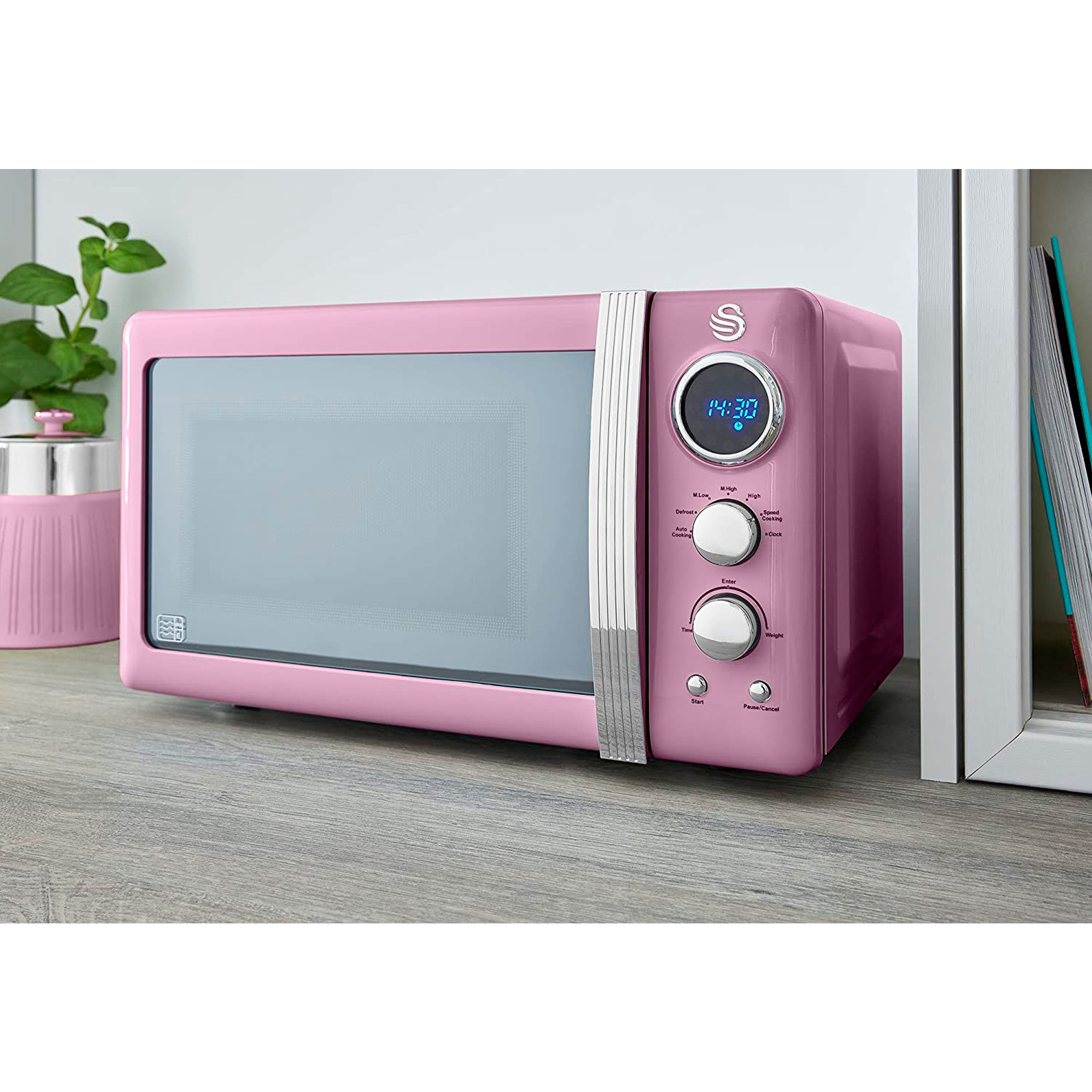 Horno microondas retro rosa sobre una superficie de madera.