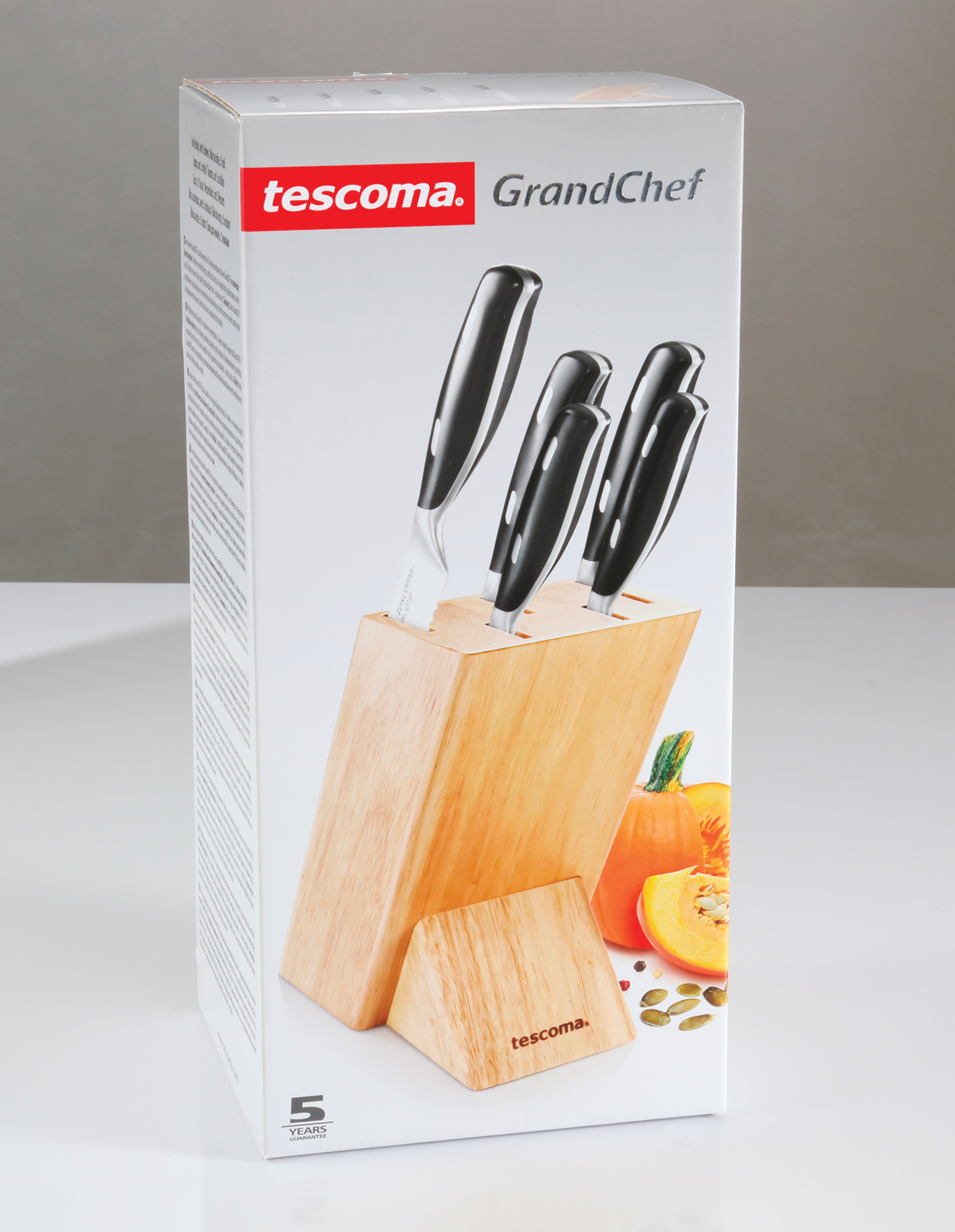 Karton mit Tescoma GrandChef Messern in Holzblock, mit Kürbis, weißer Hintergrund.