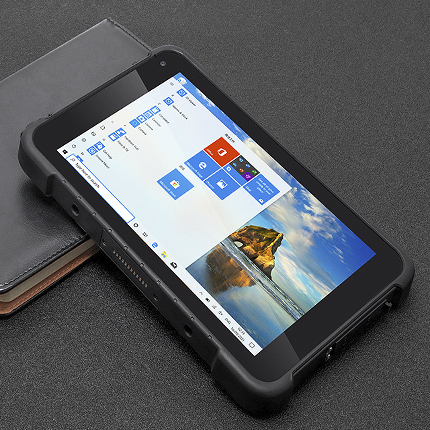Un tablet nero che mostra un'interfaccia Windows, accanto a un libro chiuso.