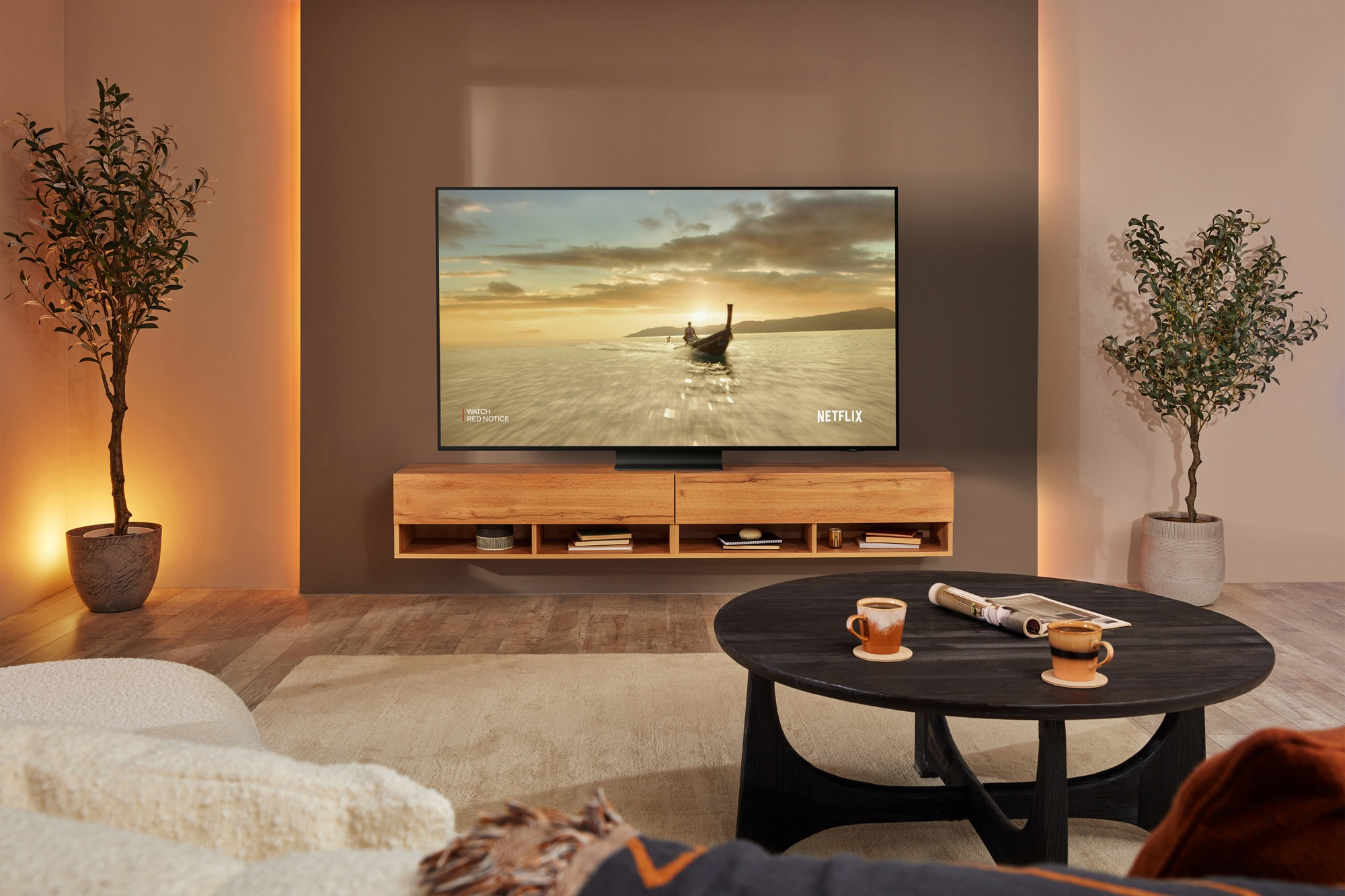 Soggiorno con TV su una console in legno, un divano e un tavolino rotondo con due tazze.