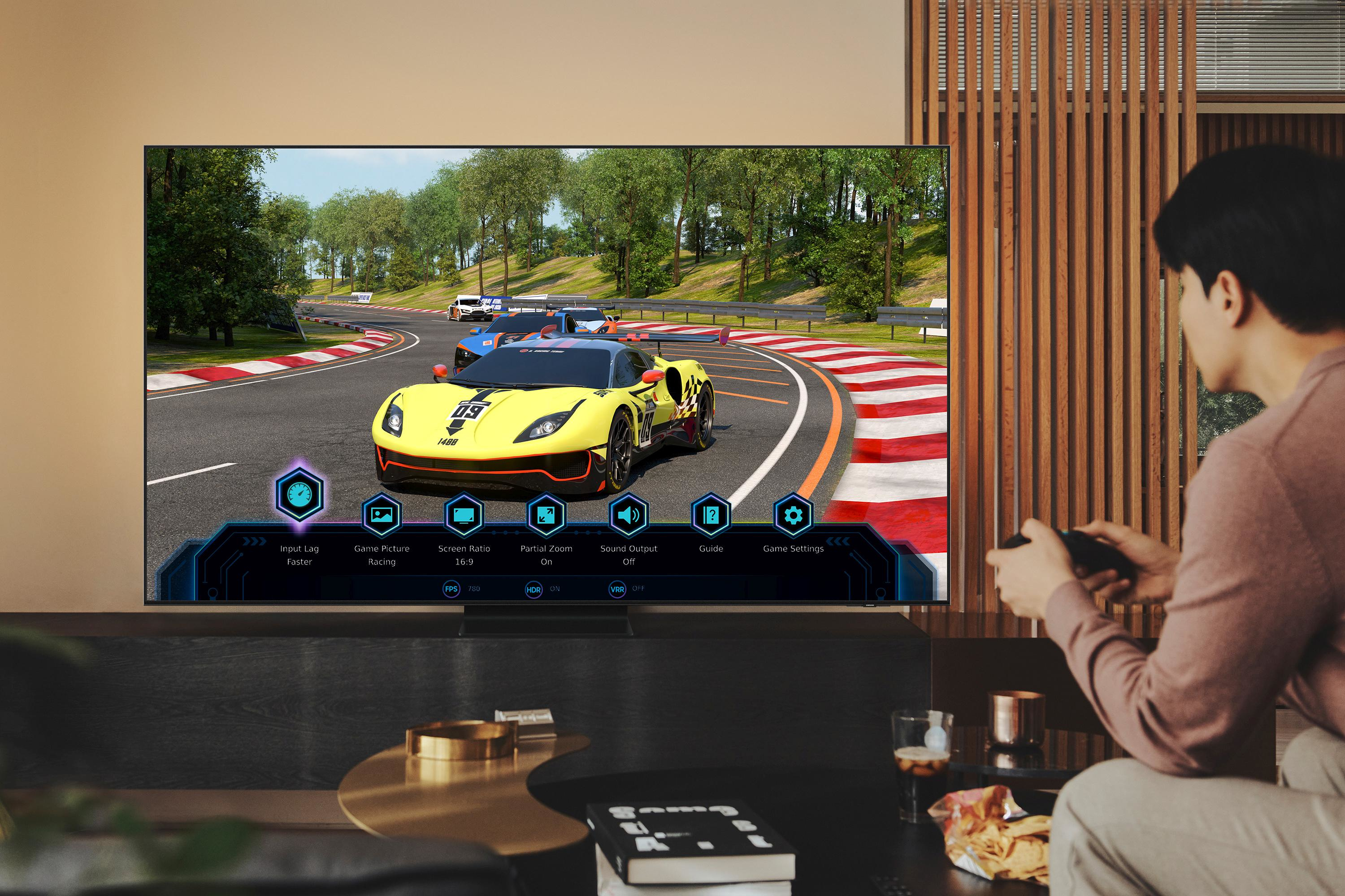 Uomo che gioca a un gioco di corse in TV. La TV mostra un'auto da corsa gialla.