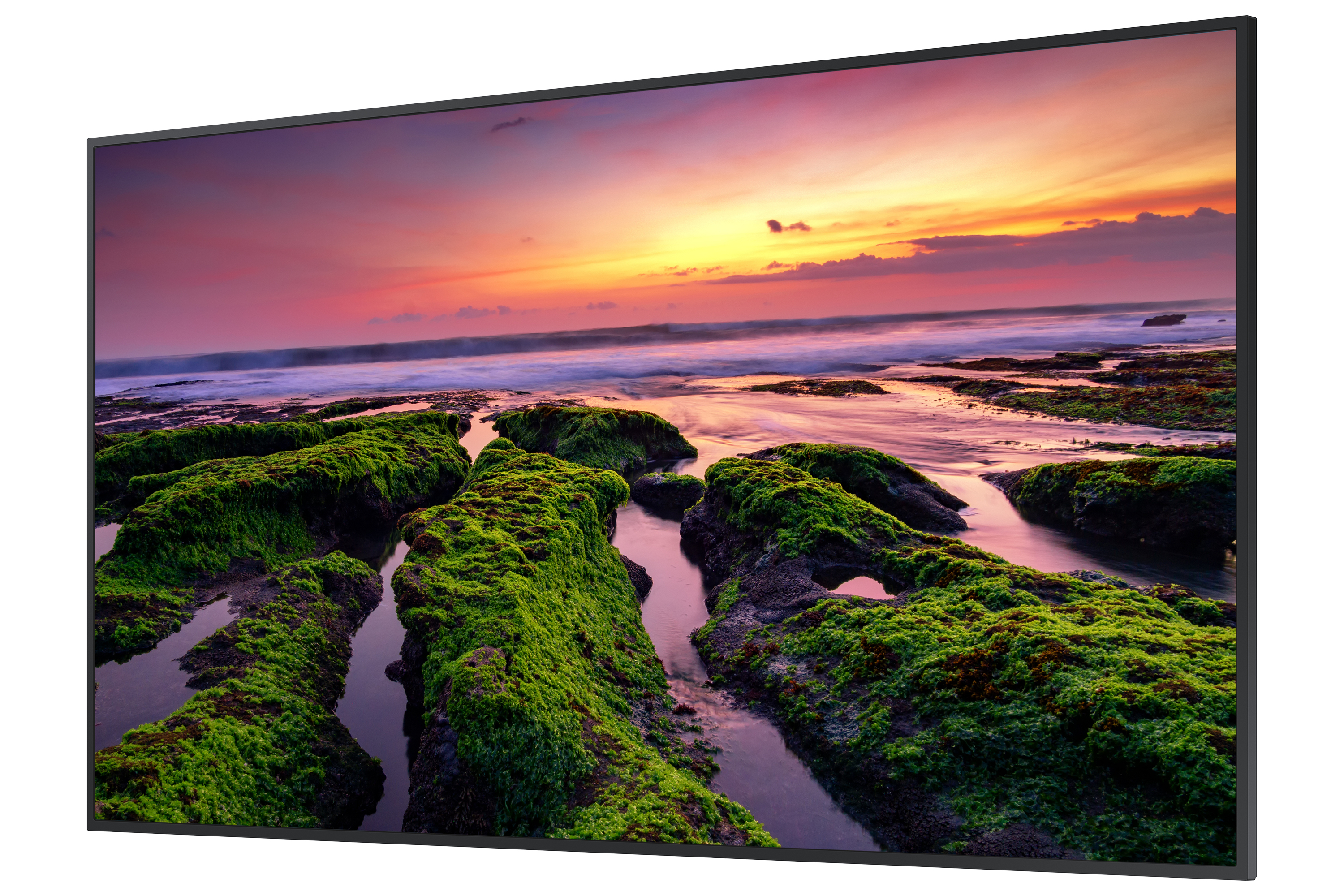 Großer Fernseher zeigt Sonnenuntergang über dem Ozean, mit Felsen im Vordergrund.