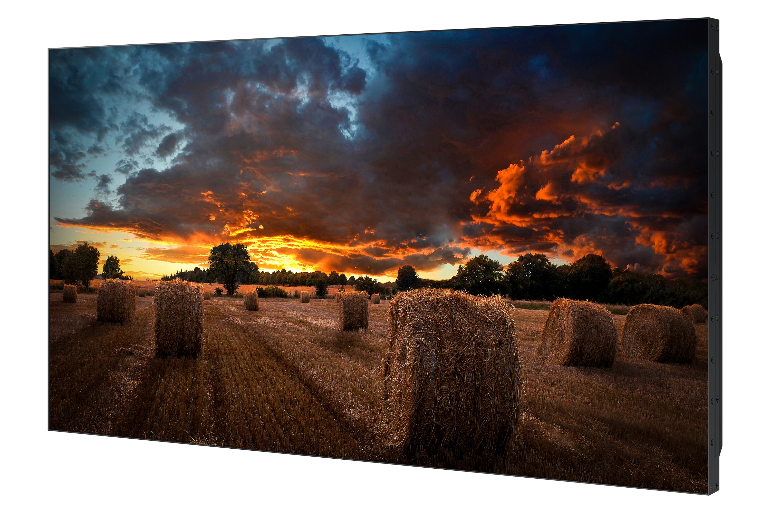 Heuballen auf einem Feld unter einem dramatischen Sonnenuntergang mit bewölktem Himmel.