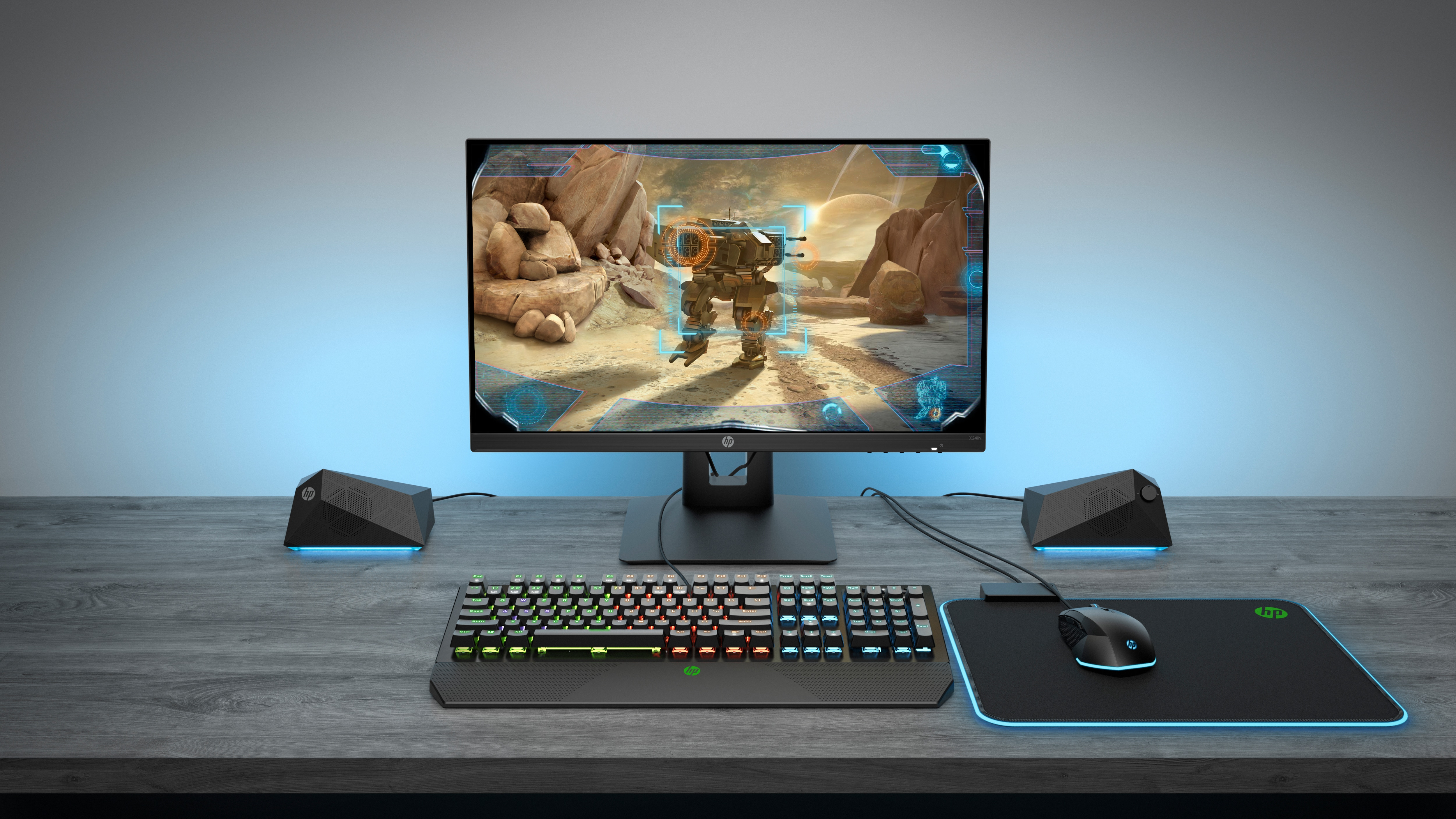Configuración gaming con monitor, teclado, ratón y altavoces en escritorio.