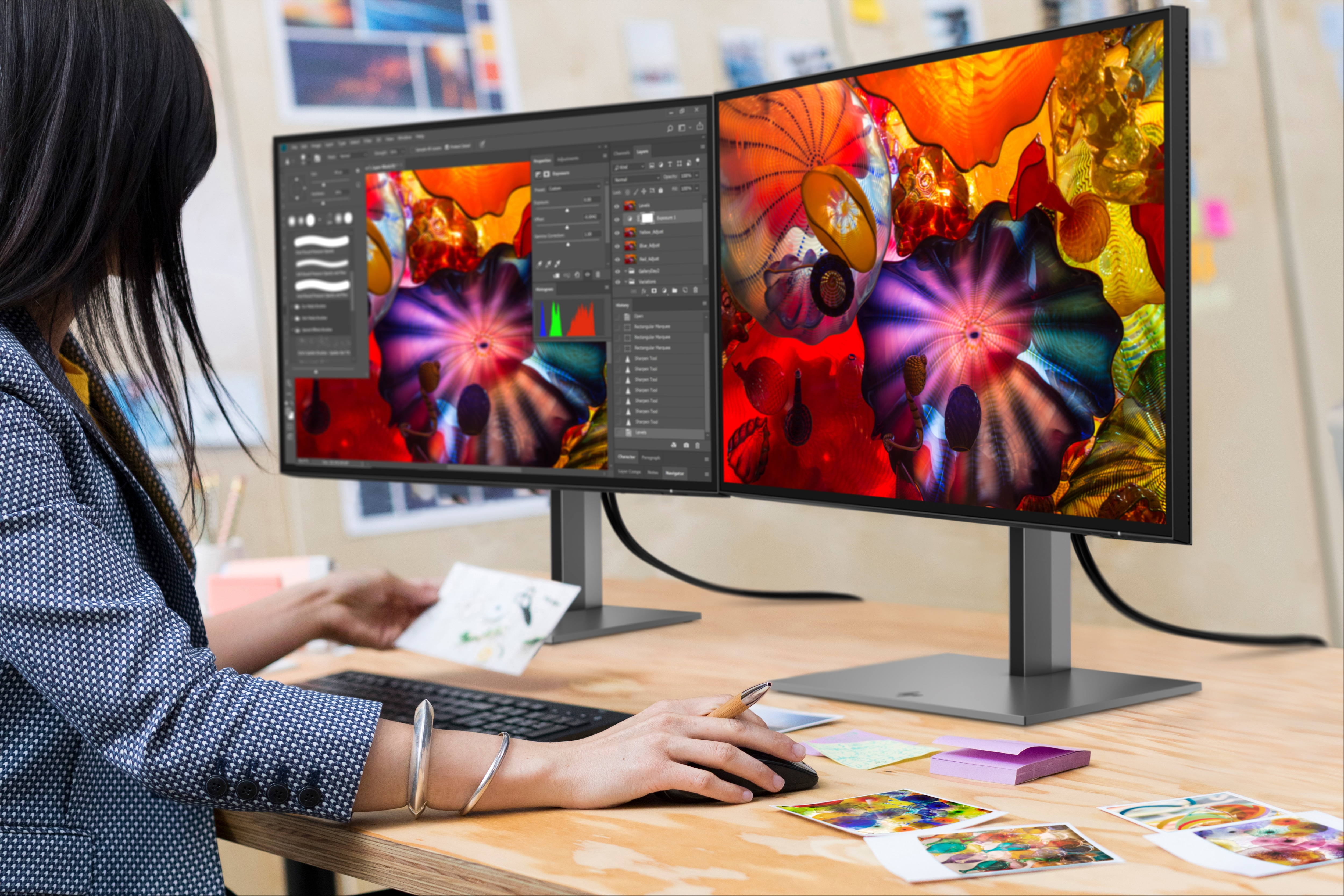 Frau benutzt zwei HP-Monitore mit Designsoftware.