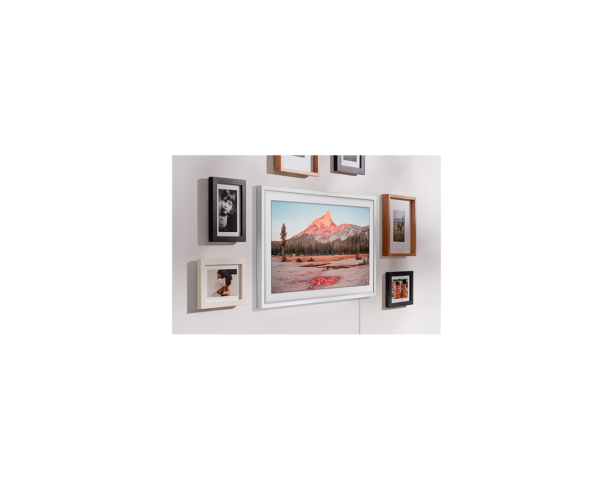 Obrazy w ramkach na ścianie. Niektóre to czarne, białe i drewniane ramki.