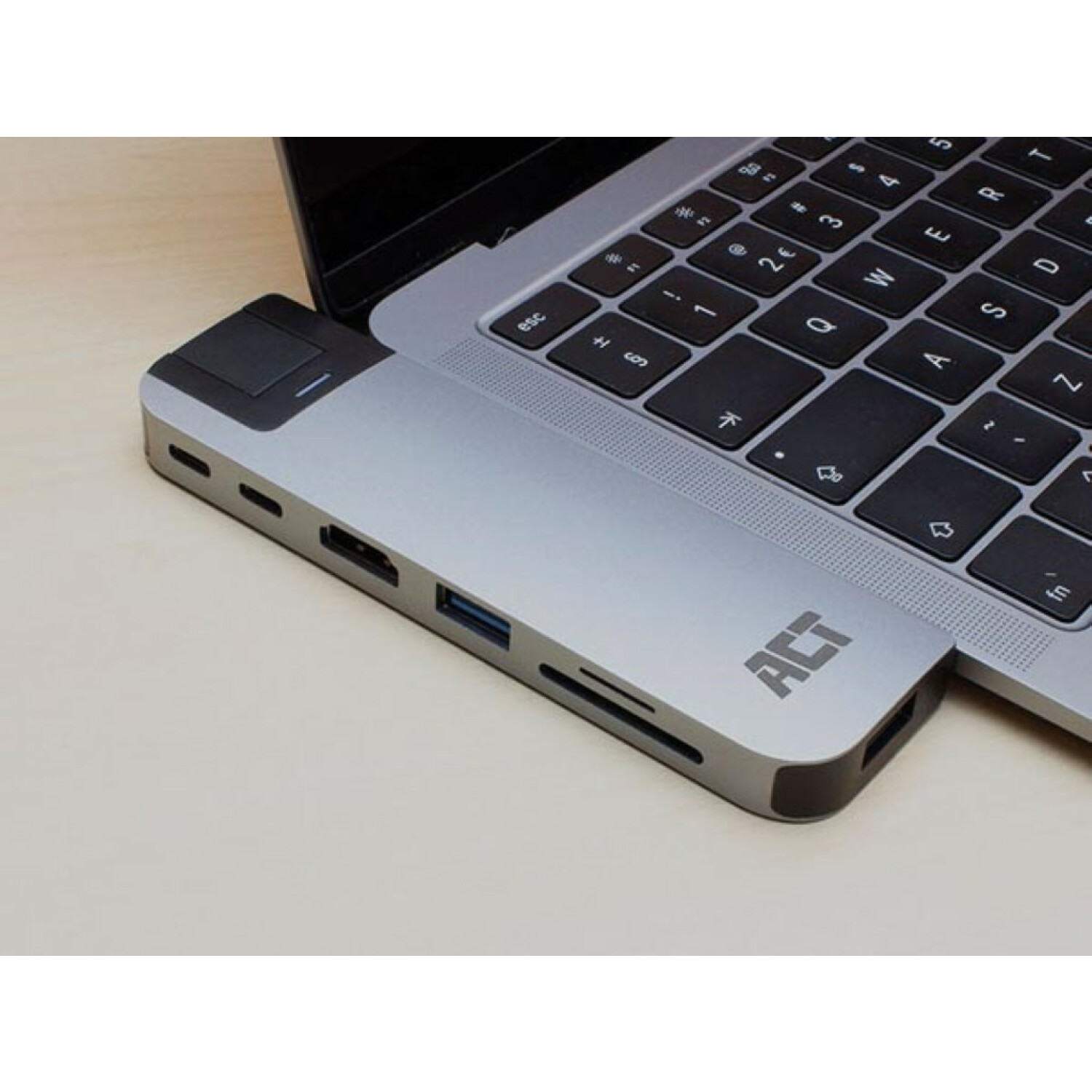 Laptop und ein silberner Hub mit Anschlüssen, die mit dem Laptop verbunden sind.