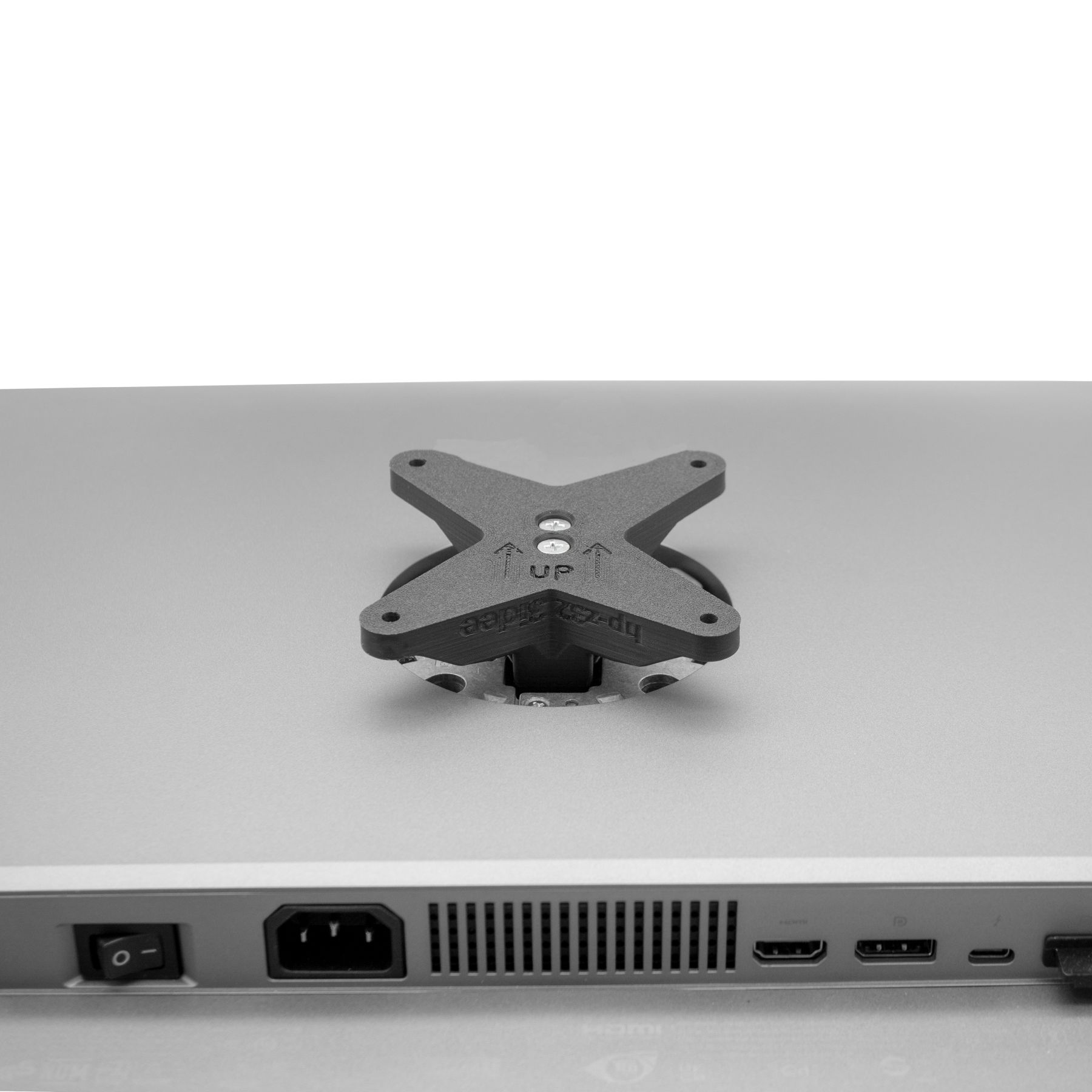 Monitorrückseite mit X-förmiger Montageplatte. Pfeil nach oben und Anschlüsse sichtbar.