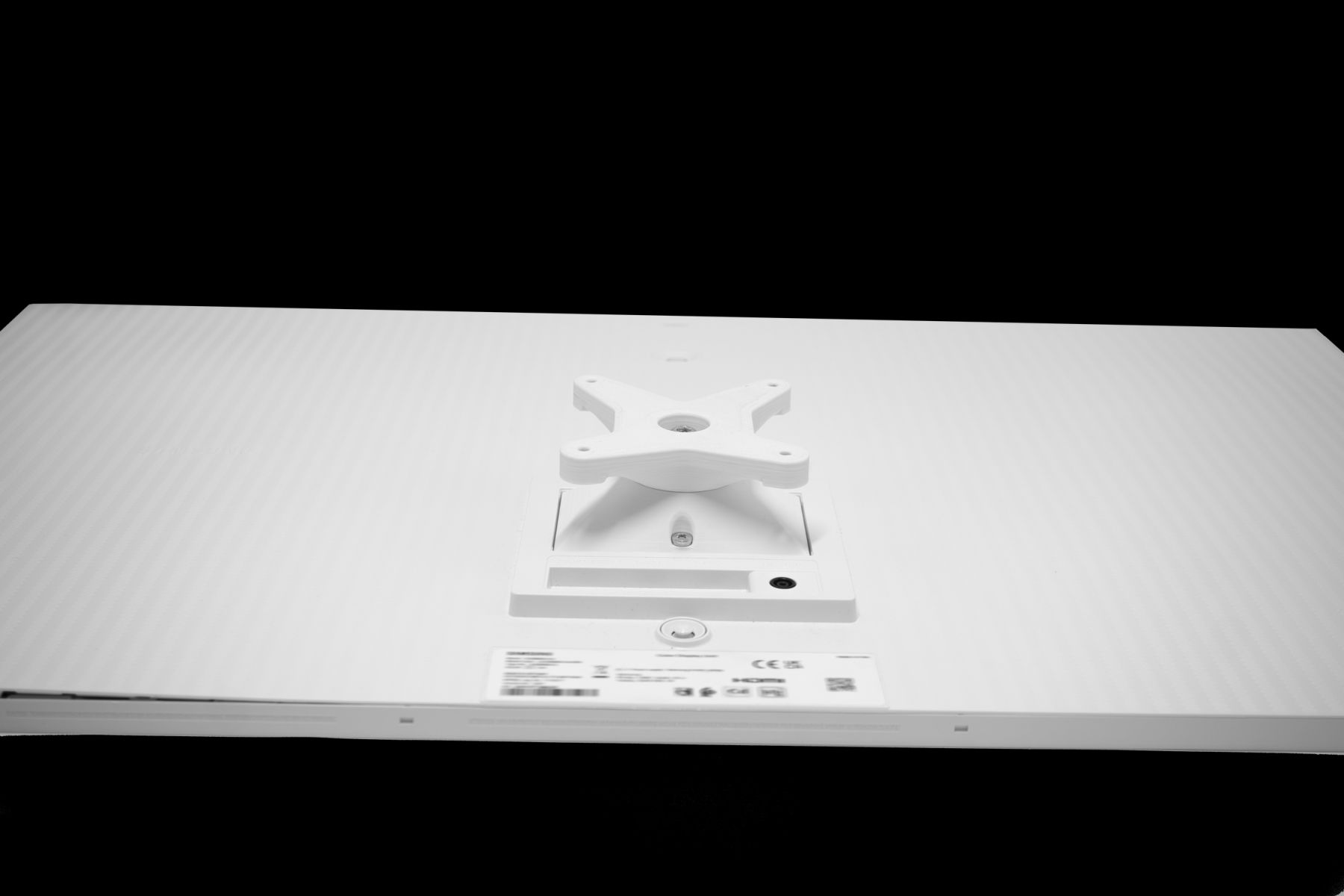 Rückseite eines weißen Monitors mit Halterung und Etikett.
