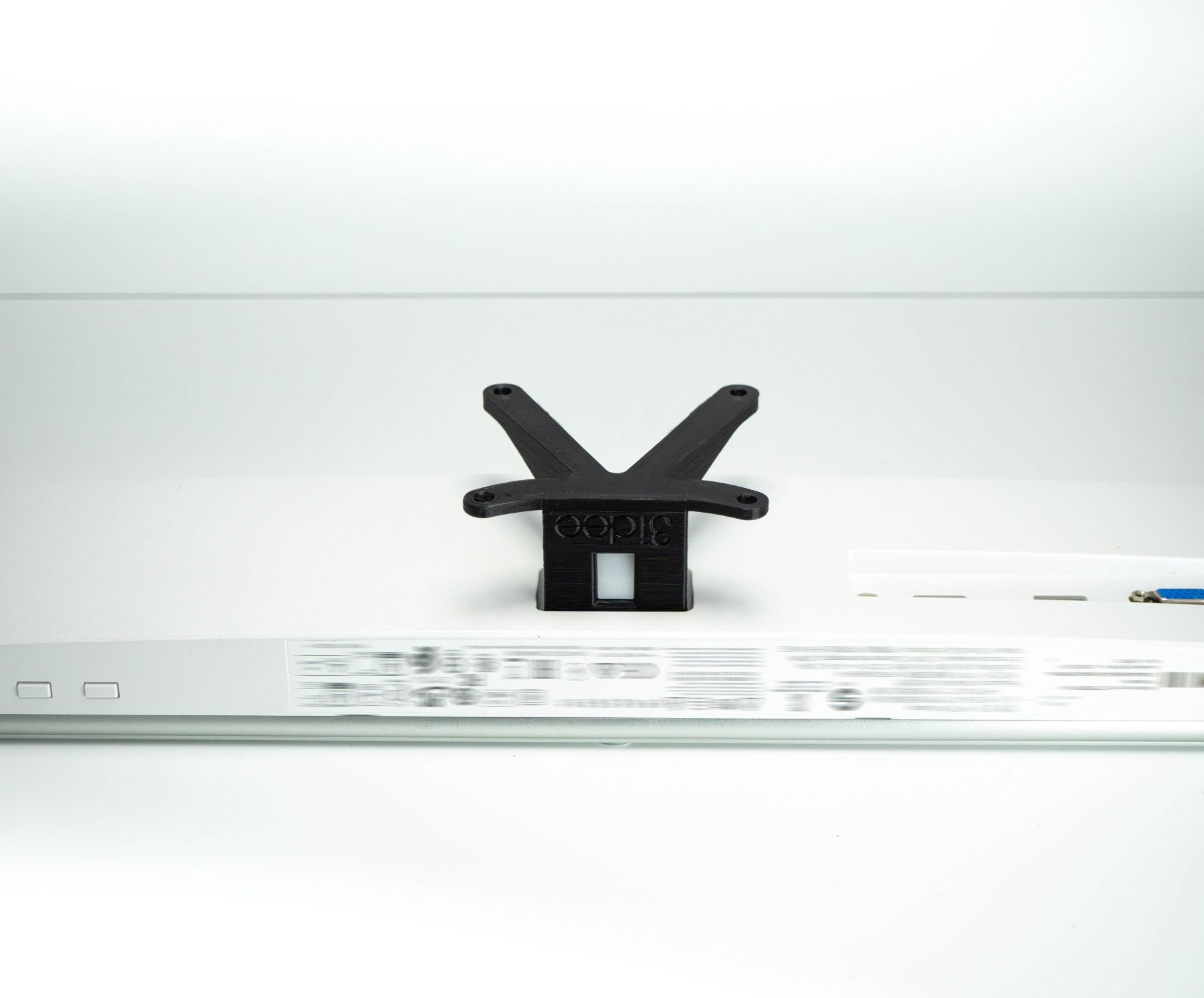 Schwarzer Ständer für einen Monitor, auf einer weißen Oberfläche montiert. Der Ständer hat V-Form.