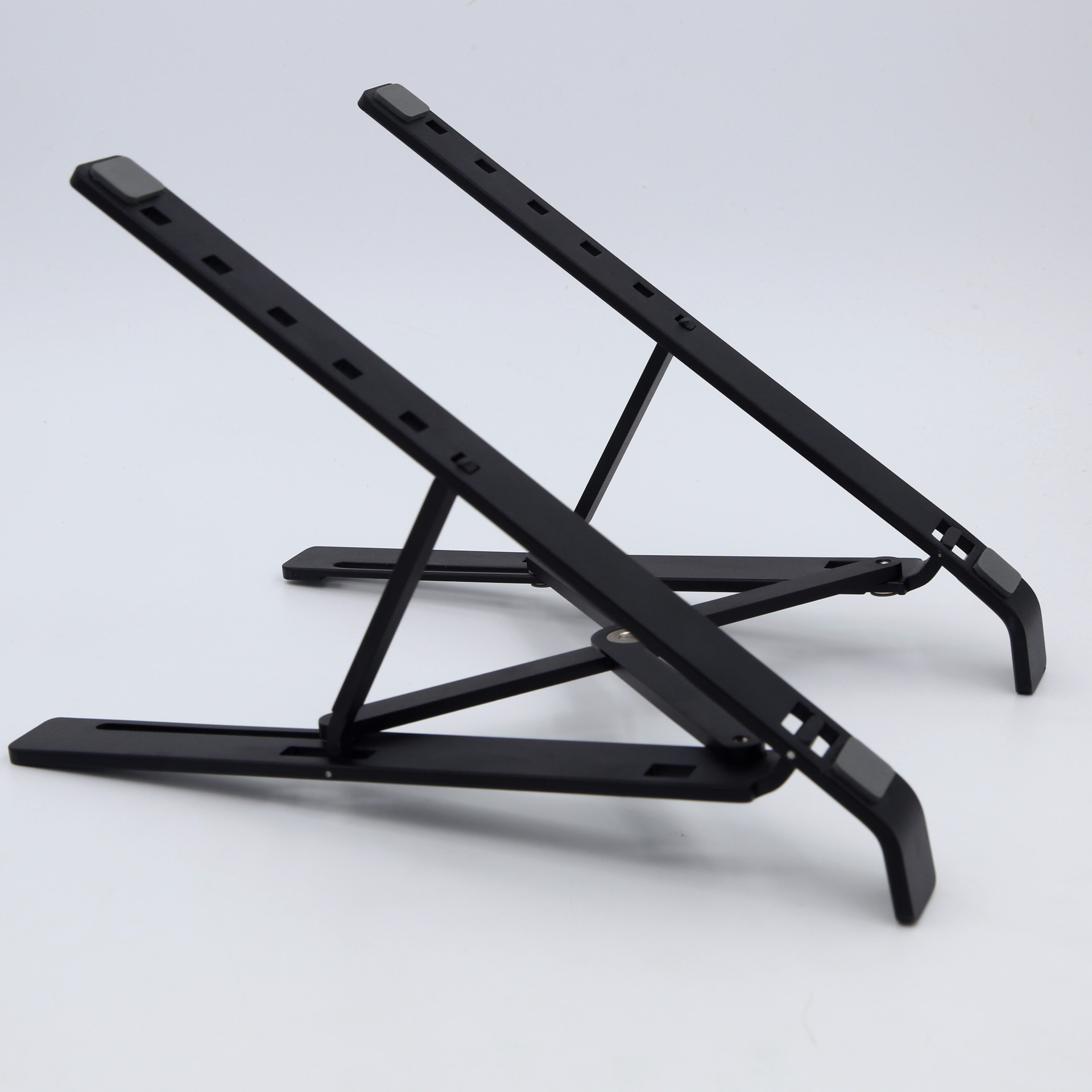 Dwa czarne stojaki na laptopa na białej powierzchni. Są pod kątem i otwarte.