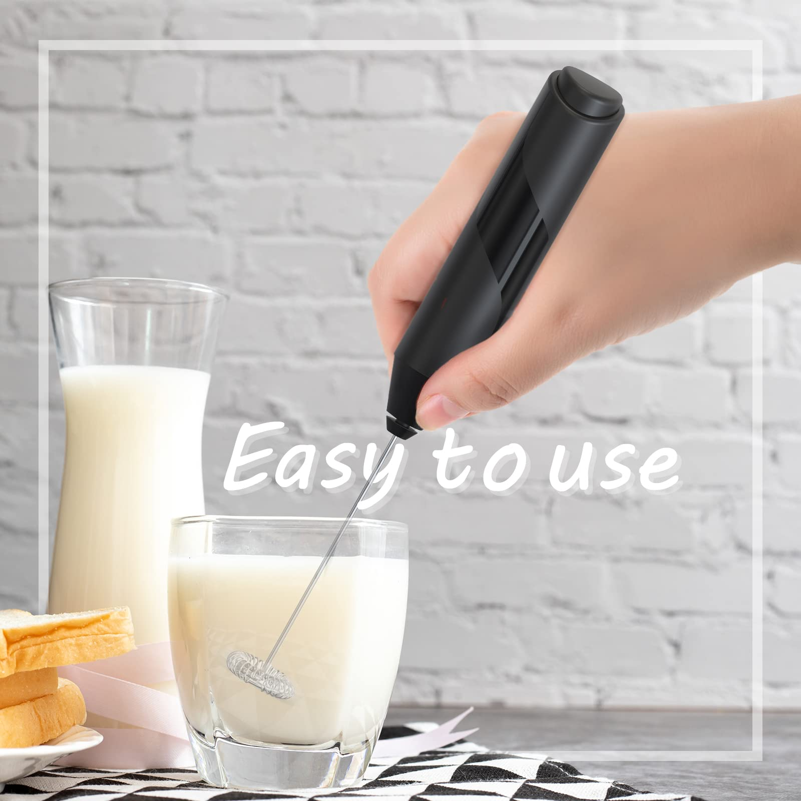 Ręka używa czarnego spieniacza do mleka do spieniania mleka w szklance. Mleko i chleb po lewej.