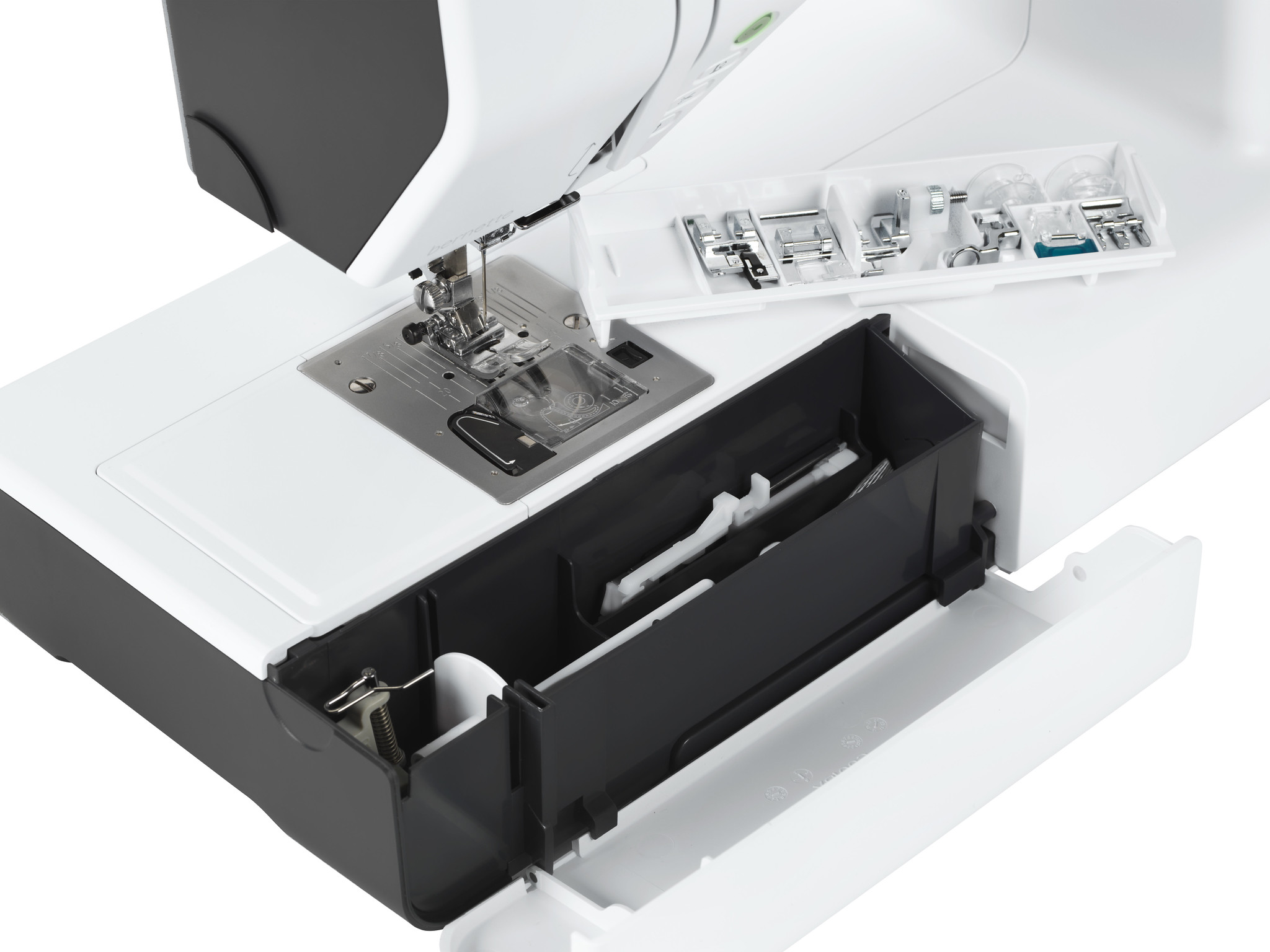 Primer plano de una máquina de coser con compartimentos abiertos, mostrando accesorios.