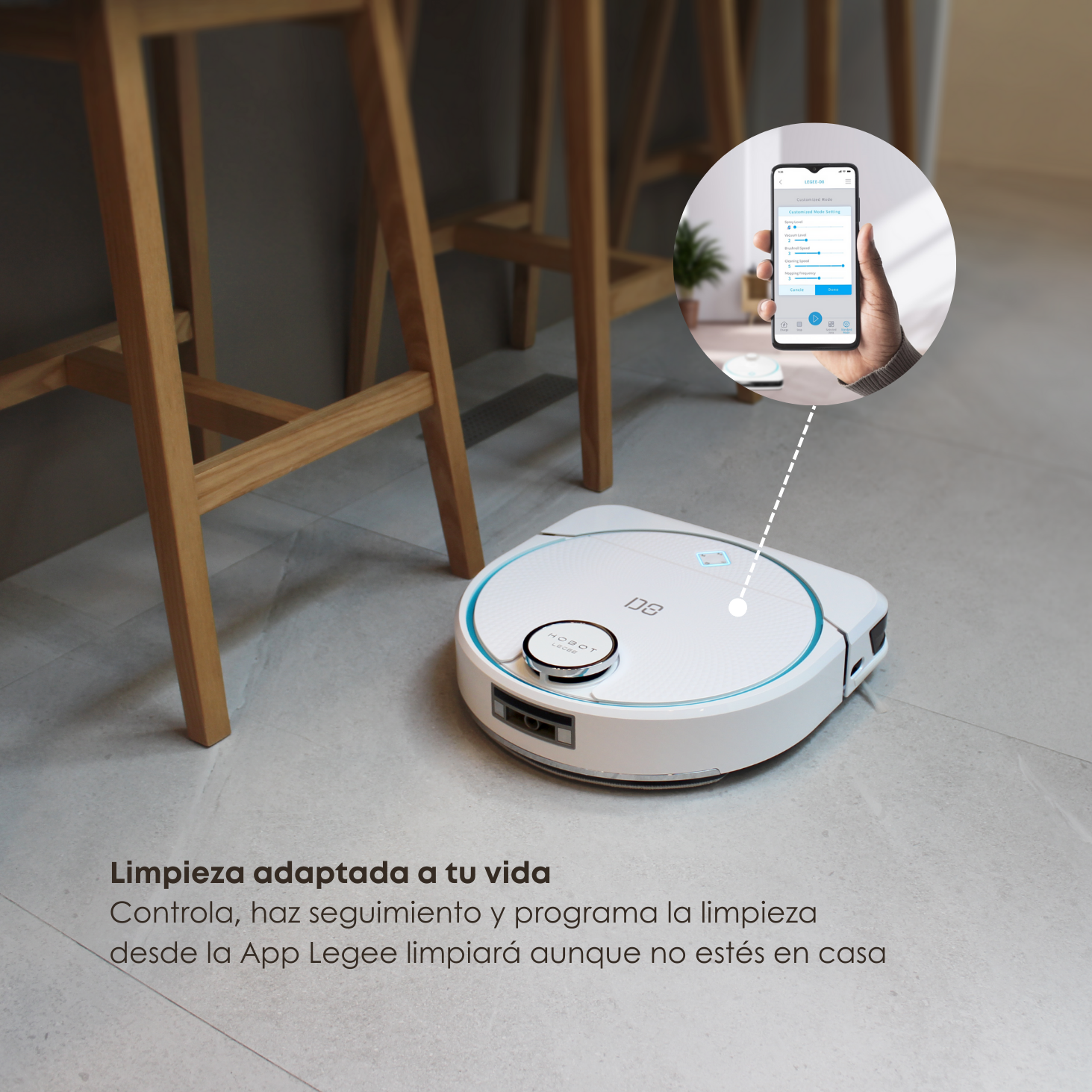 Robot aspirador en piso de baldosas, teléfono en mano, conectado a la App.
