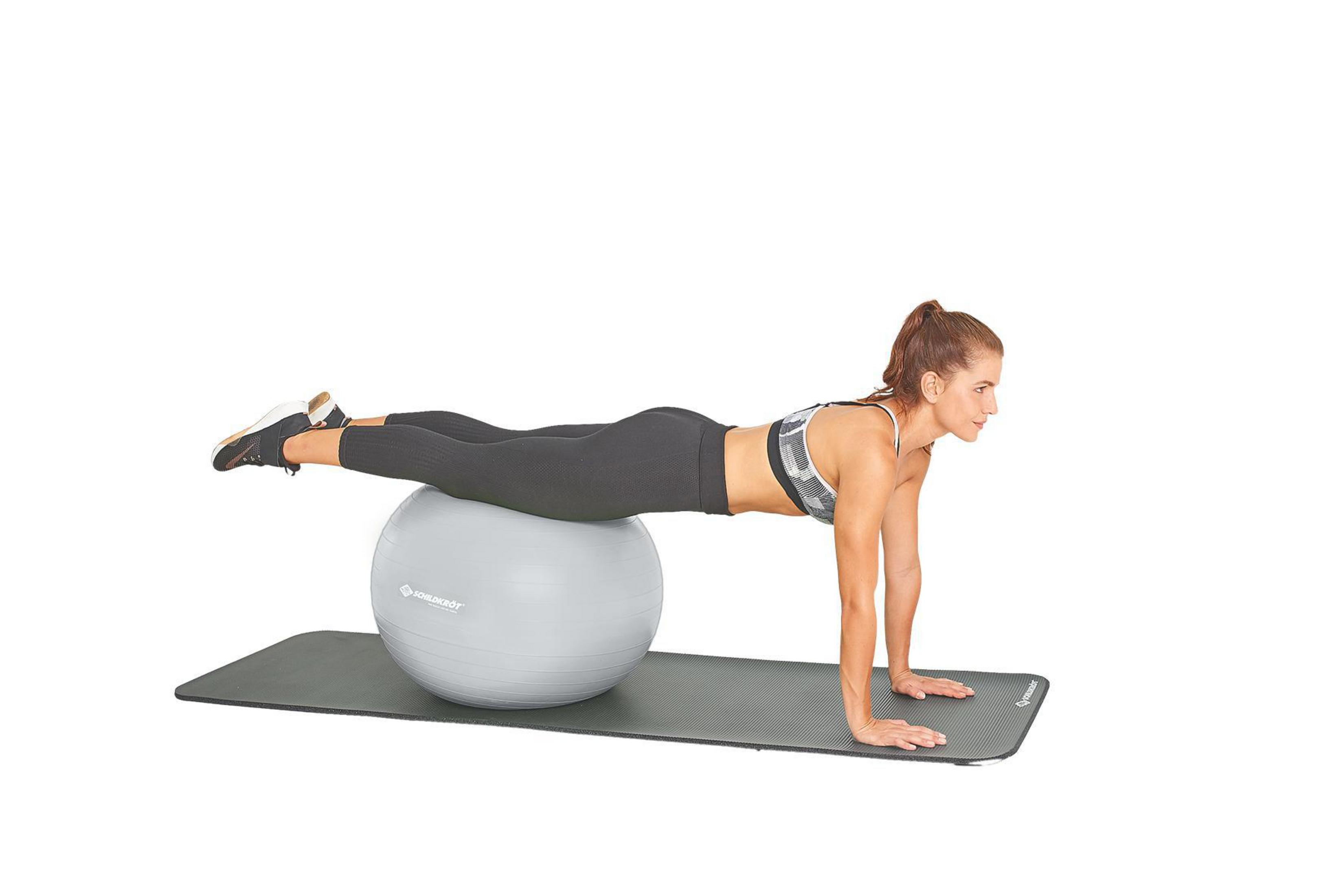 Frau auf einem grauen Gymnastikball, Plank auf einer grauen Matte. Weißer Hintergrund.