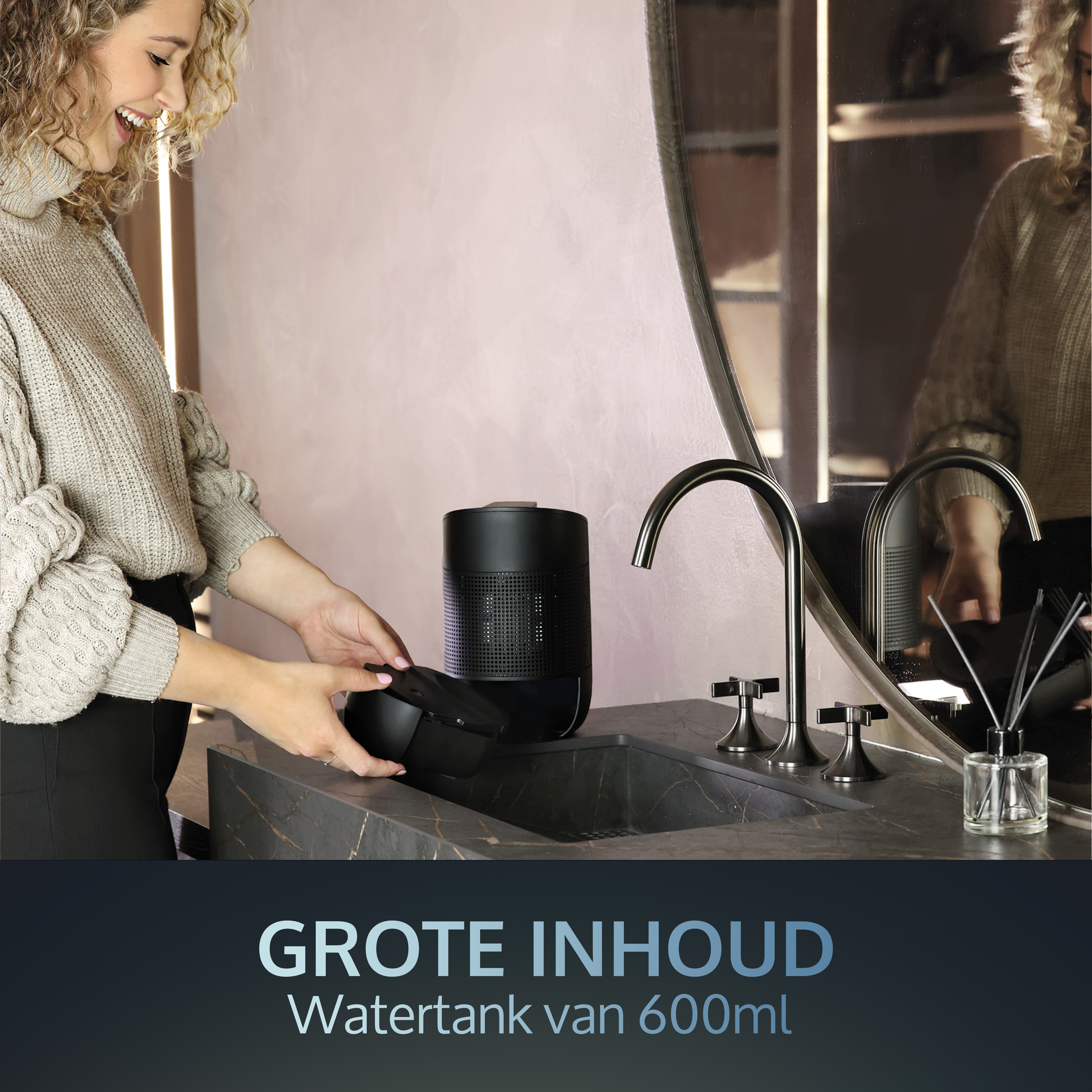 Frau in der Nähe eines Waschbeckens mit Diffusor. Schwarzer Diffusor und schwarzes Waschbecken.