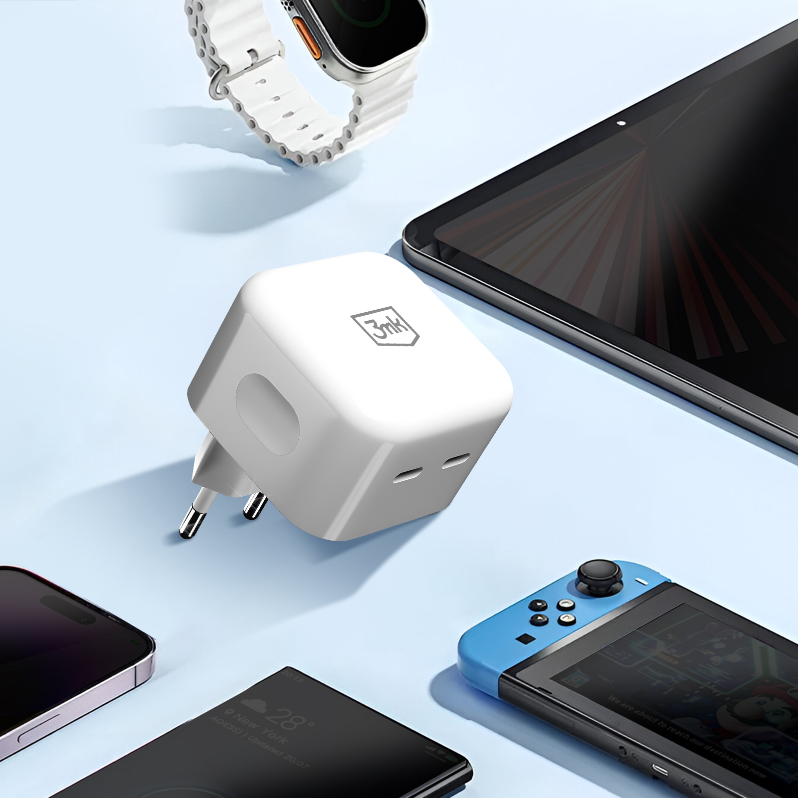 Un caricabatterie bianco con spine, accanto a un orologio, un tablet, un telefono e una console di gioco. Sfondo blu.